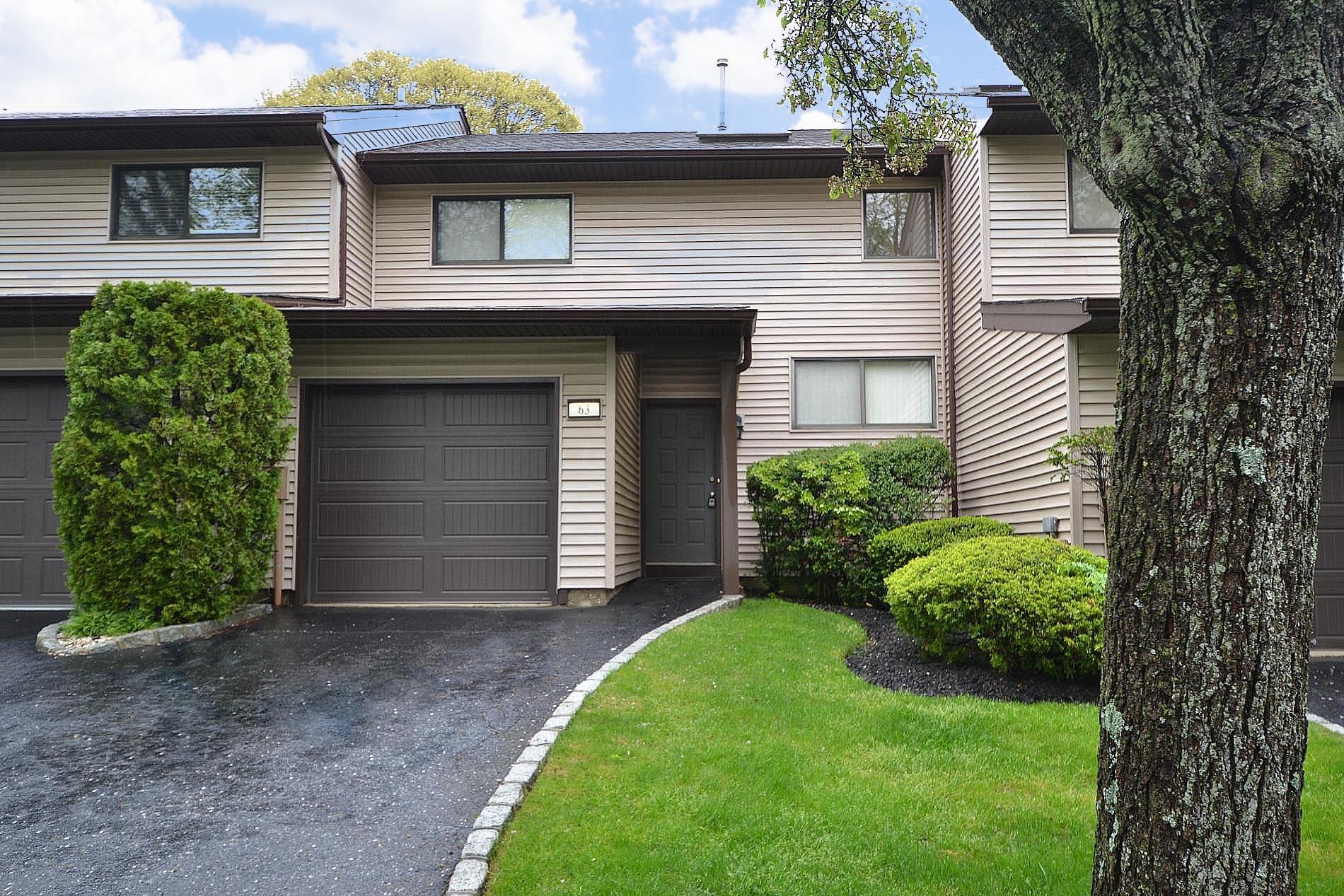 Townhome / multi-family property with an attached garage, driveway, and a front lawn