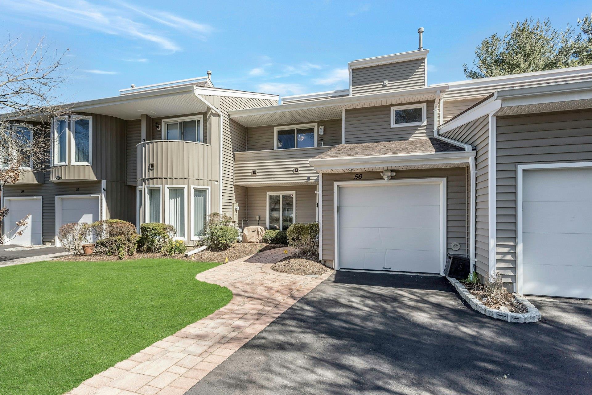 Townhome / multi-family property with a balcony, driveway, a front yard, and an attached garage