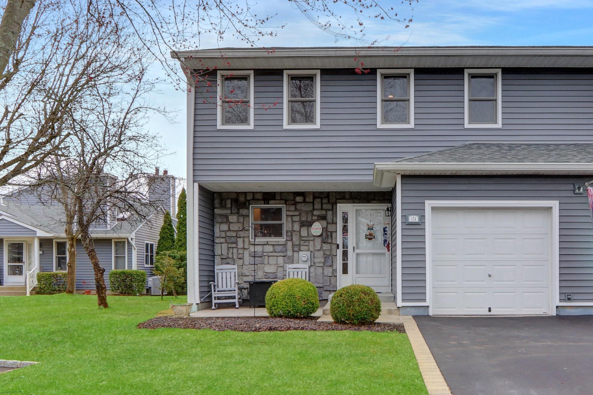 View of front of home featuring stone siding, an attached garage, a shingled roof, and a front lawn