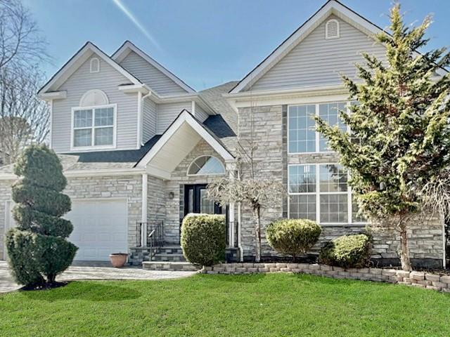 Traditional-style home featuring stone siding, a garage, and a front lawn