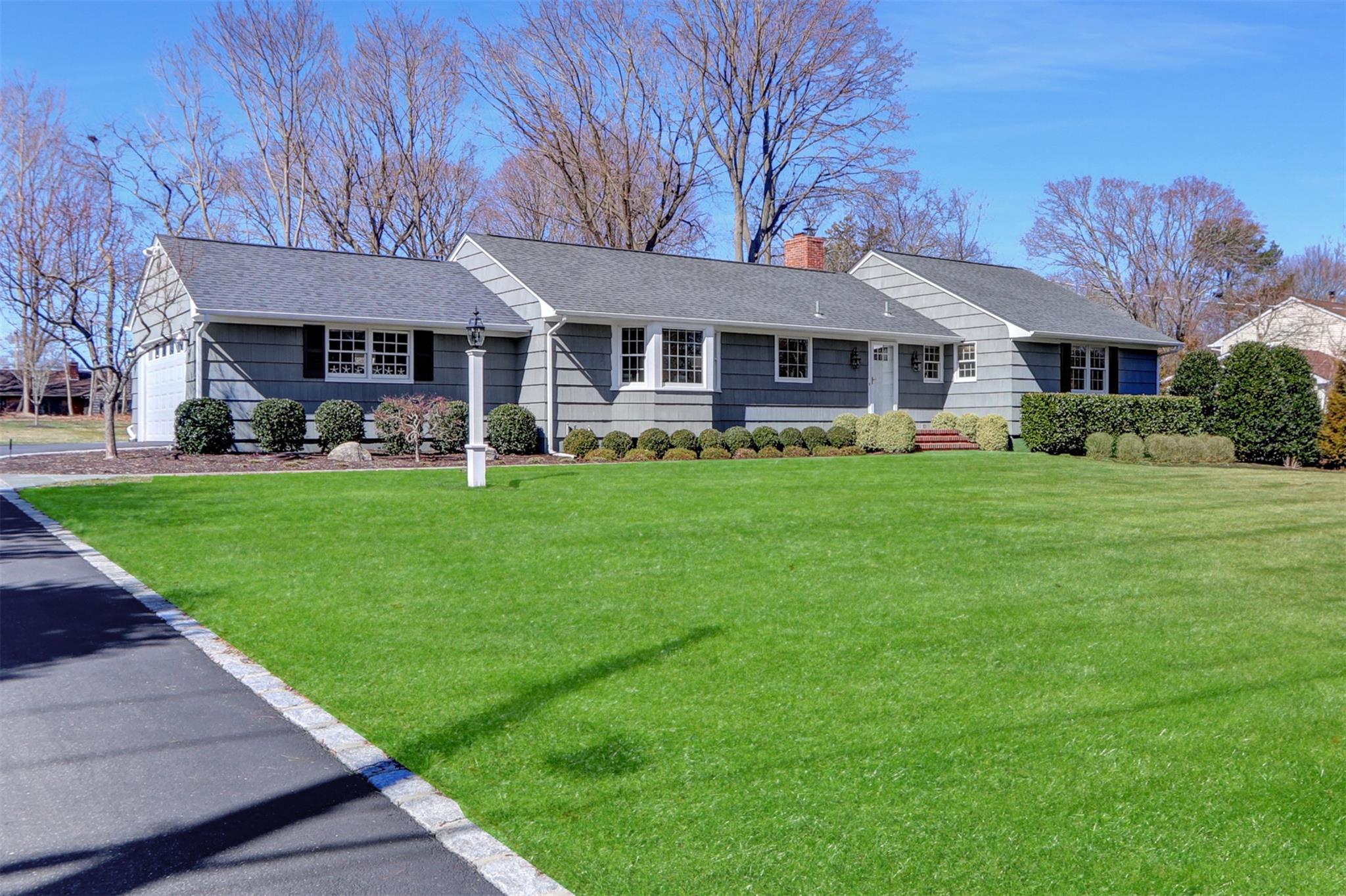 Single story home with a front lawn, a chimney, a shingled roof, and a garage