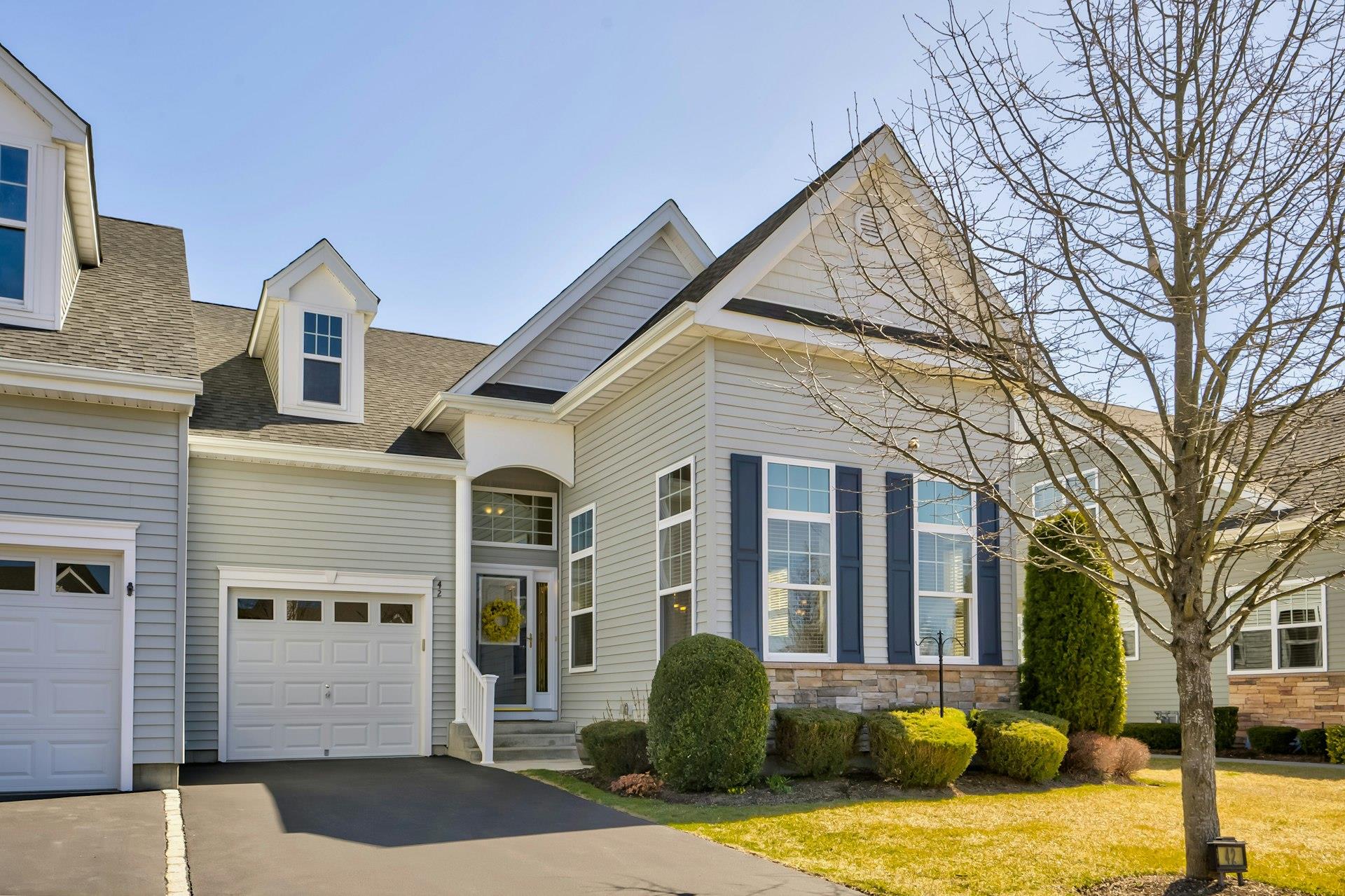 View of front of property featuring driveway, a shingled roof, a garage, and stone siding