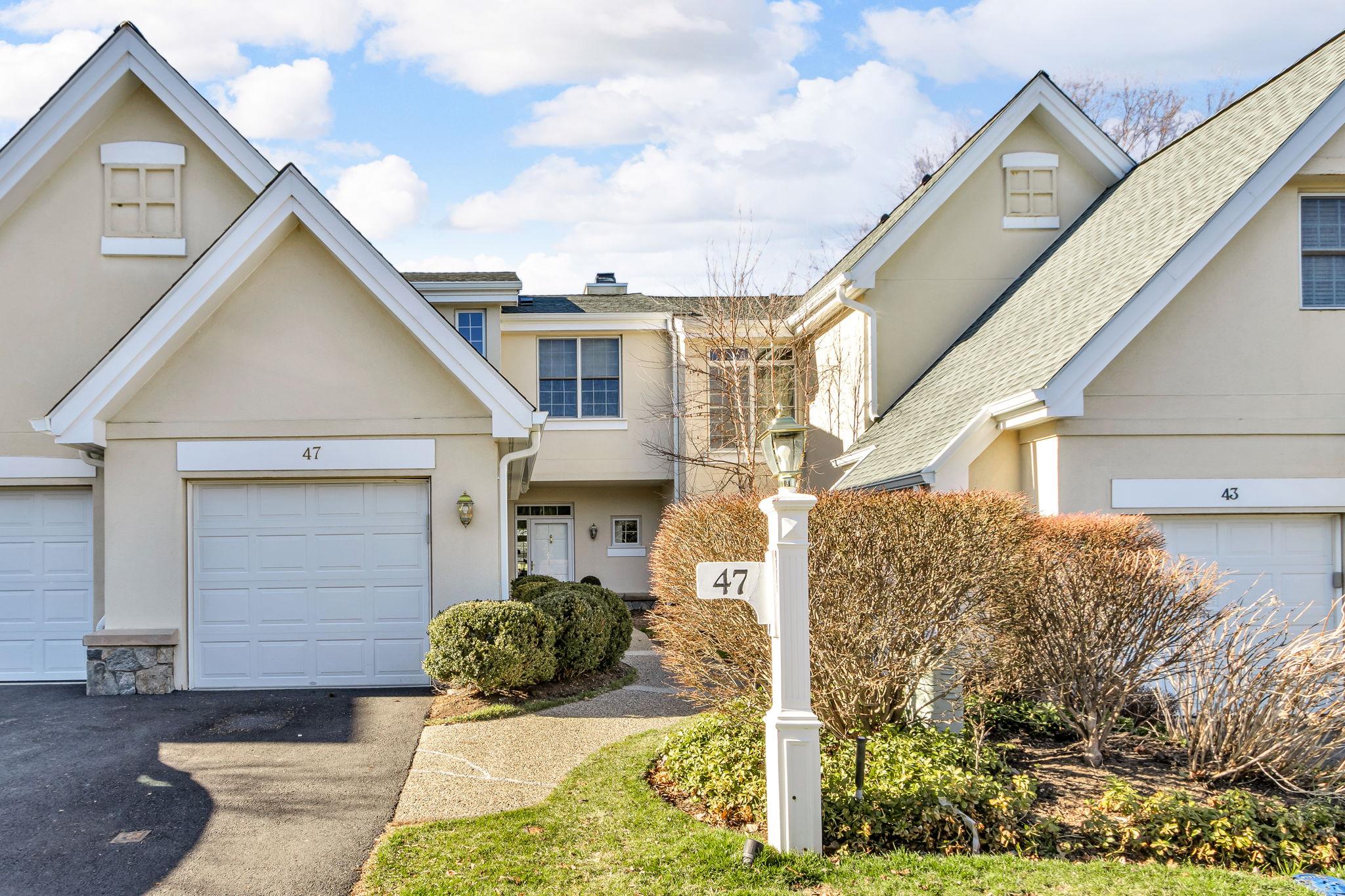 Multi unit property with stucco siding, stone siding, a garage, and roof with shingles