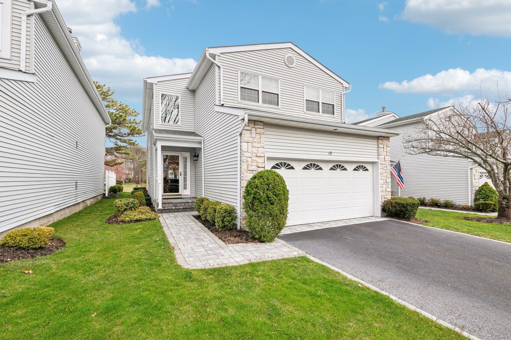 Colonial style house featuring stone & vinyl siding, a 2-car garage, and a front yard