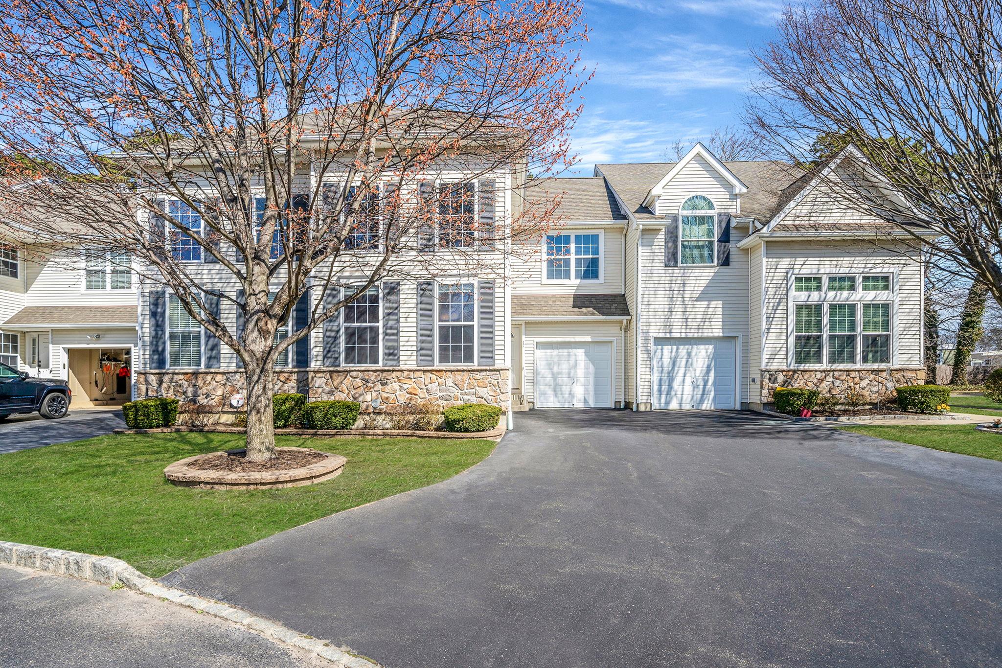 View of front facade with stone siding, driveway, a garage, and a front lawn