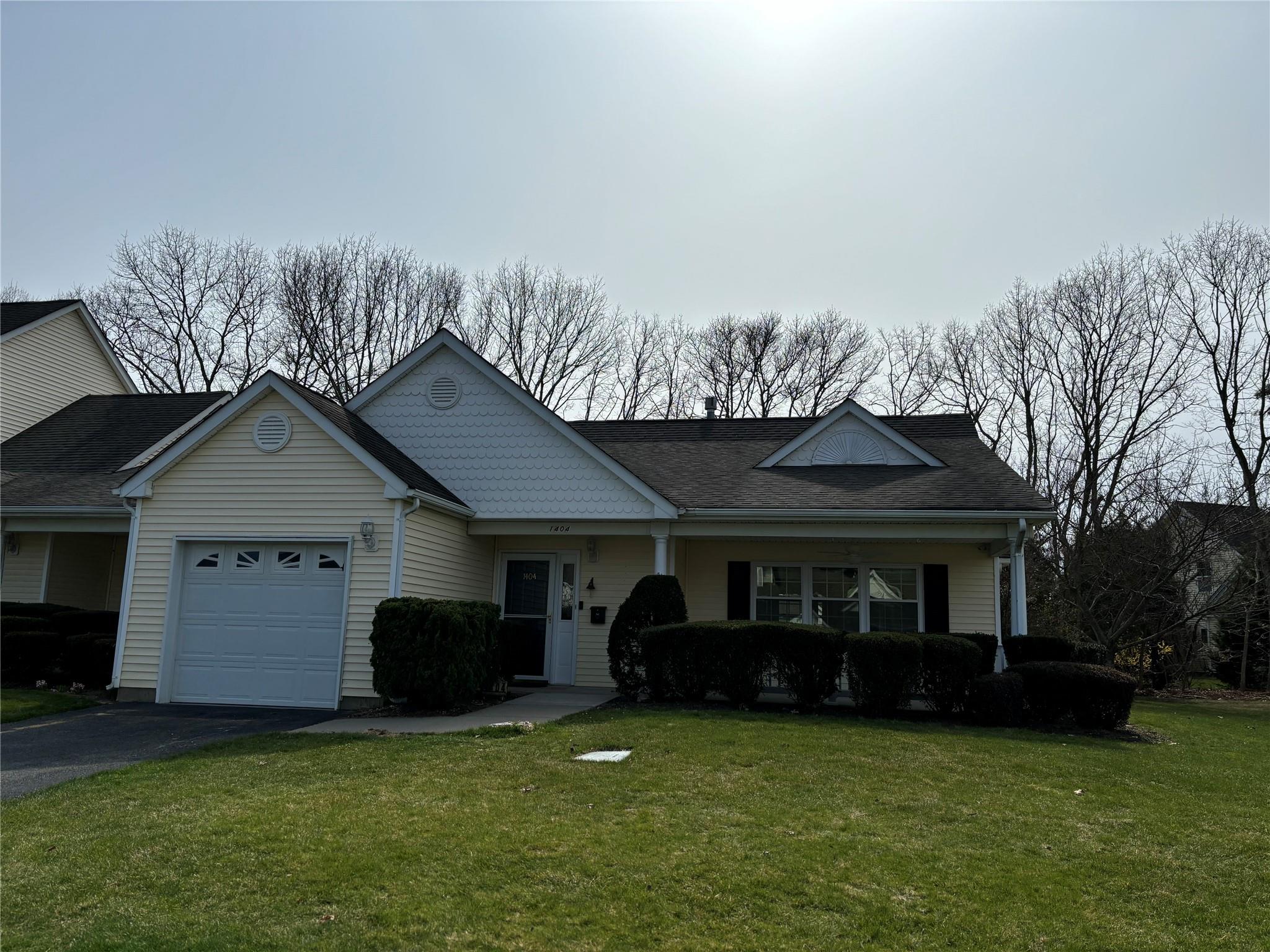 View of front of home featuring a front yard, an attached garage, a shingled roof, and driveway