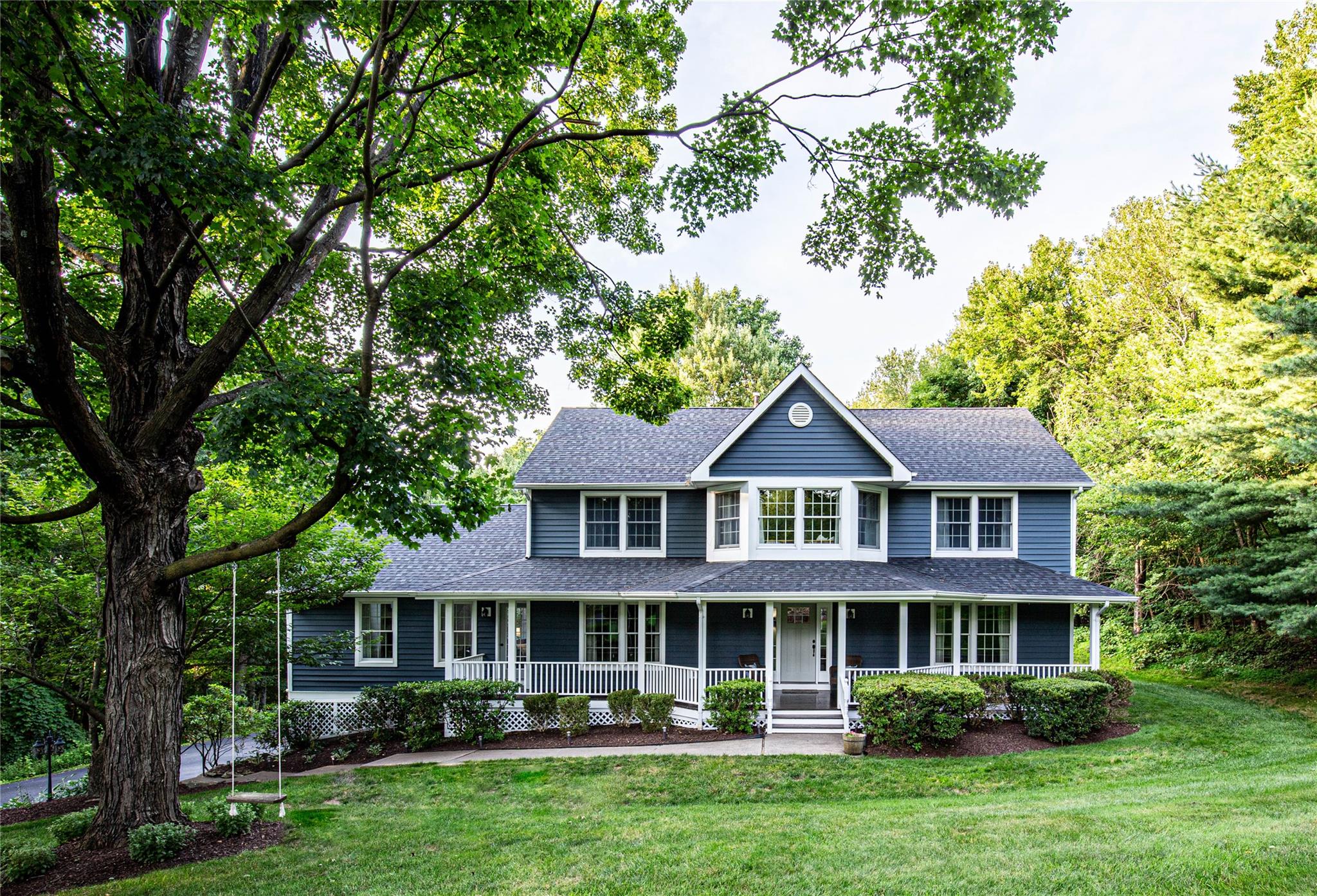 View of front of house with a front lawn, a shingled roof, and covered porch