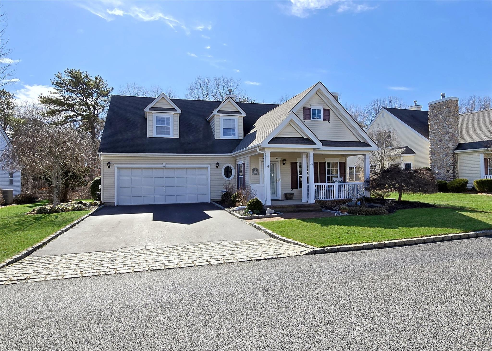 View of front of home featuring driveway, covered porch, a garage, and a front lawn