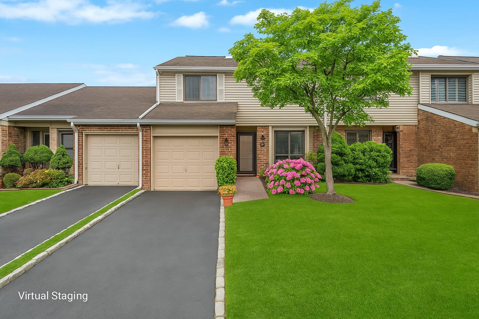 View of property featuring aphalt driveway, roof with shingles, brick siding, and a front yard