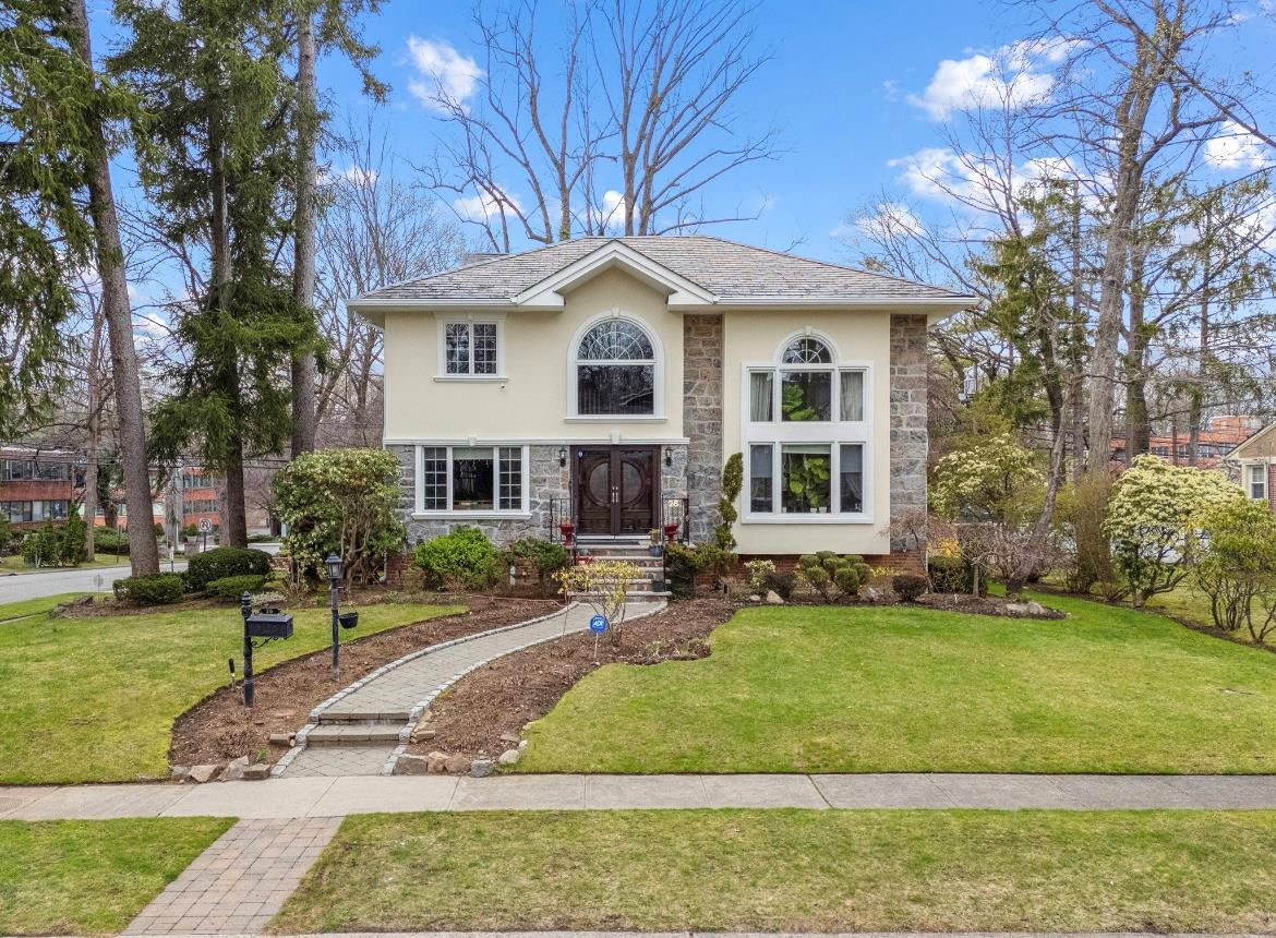 View of front of house with stucco siding, stone siding, and a front lawn