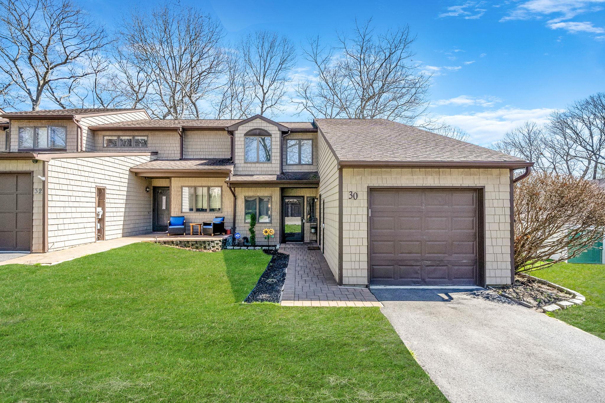 View of front of property featuring driveway, a shingled roof, an attached garage, and a front lawn