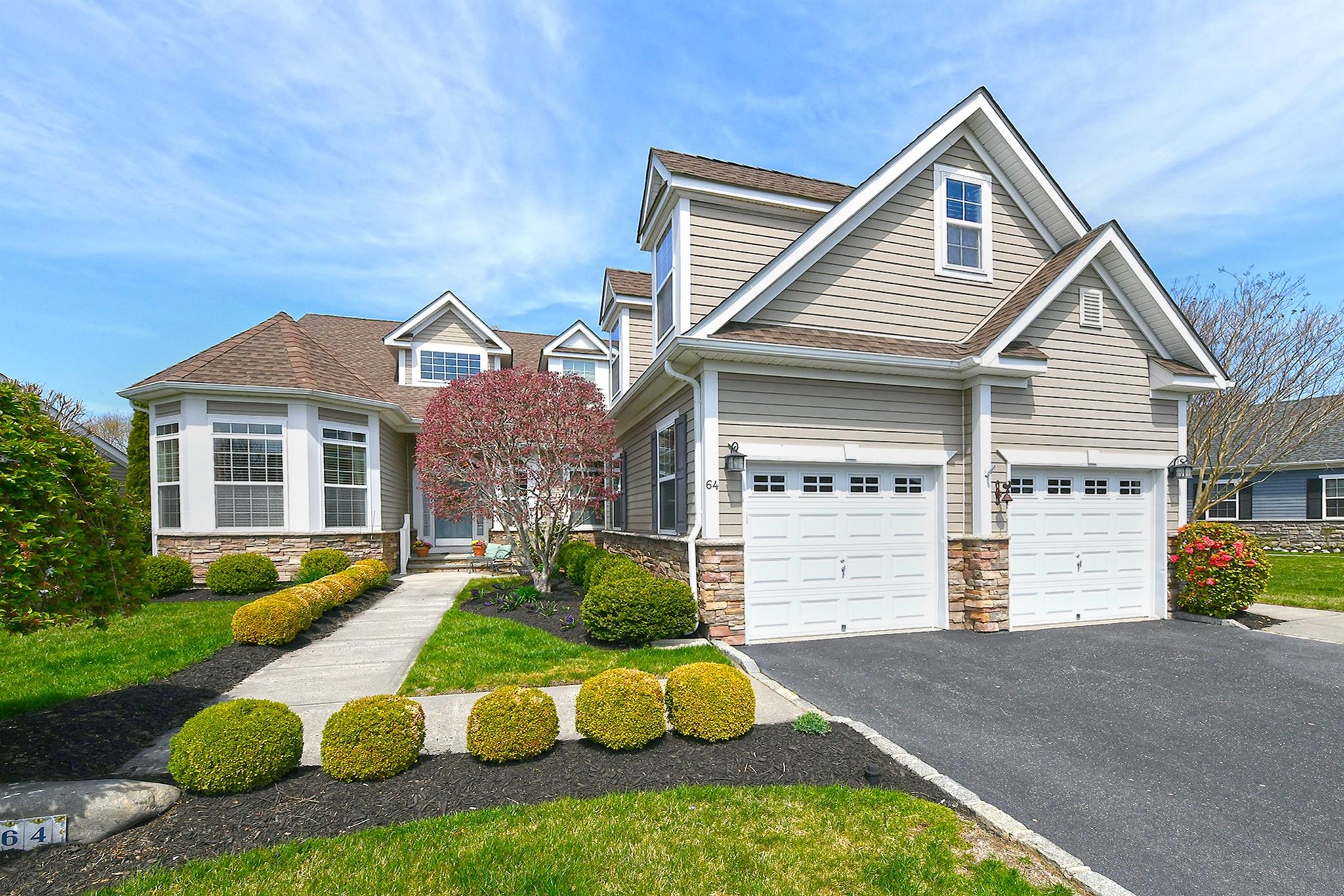 View of front of house with an attached 2-car garage, driveway, stone and hardi-plank siding