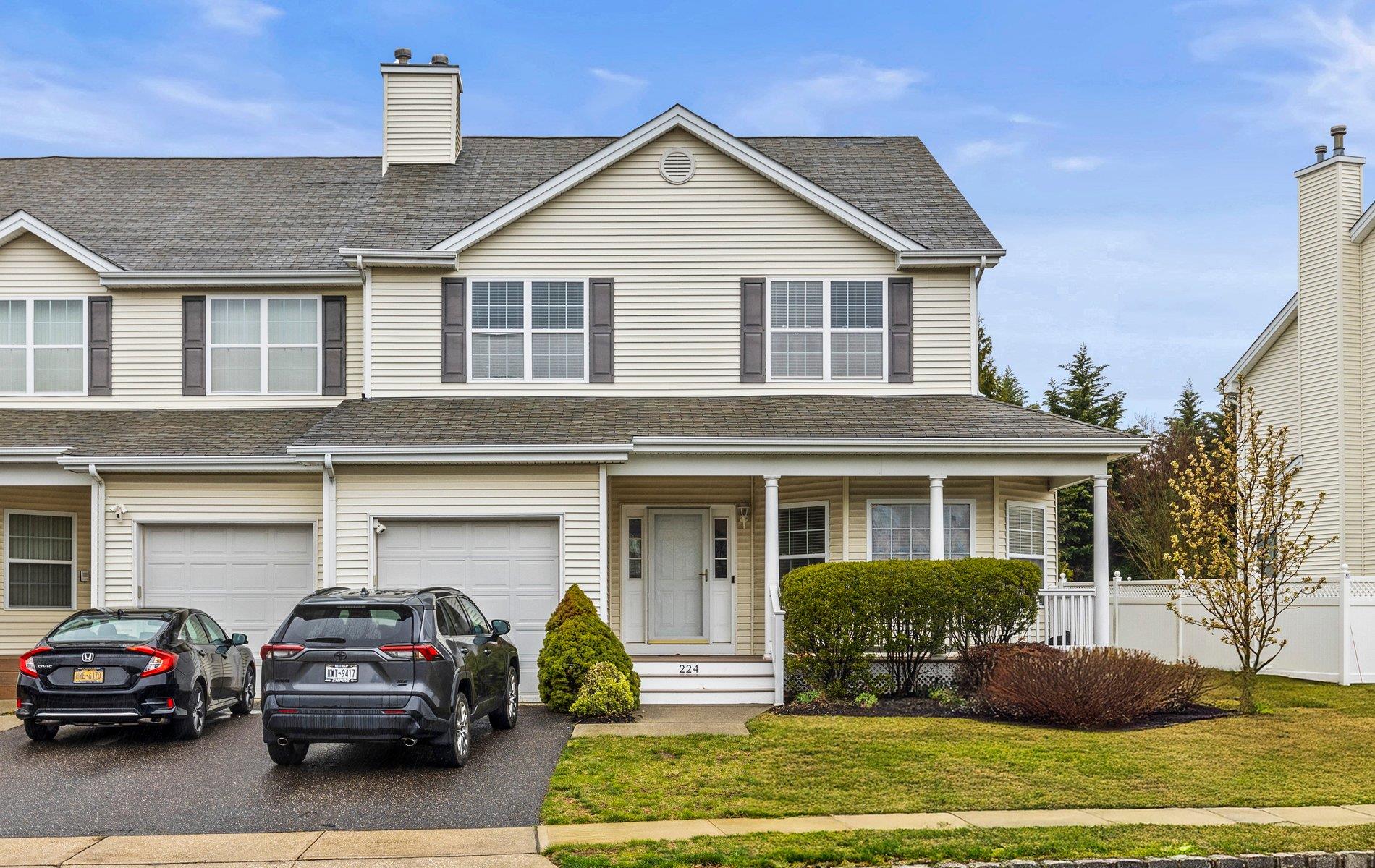 View of front facade featuring roof with shingles, driveway, a garage, and fence
