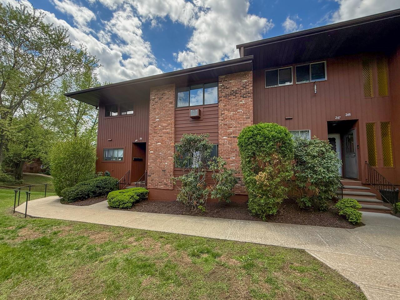View of front of home with unit access to the left featuring a yard and brick siding