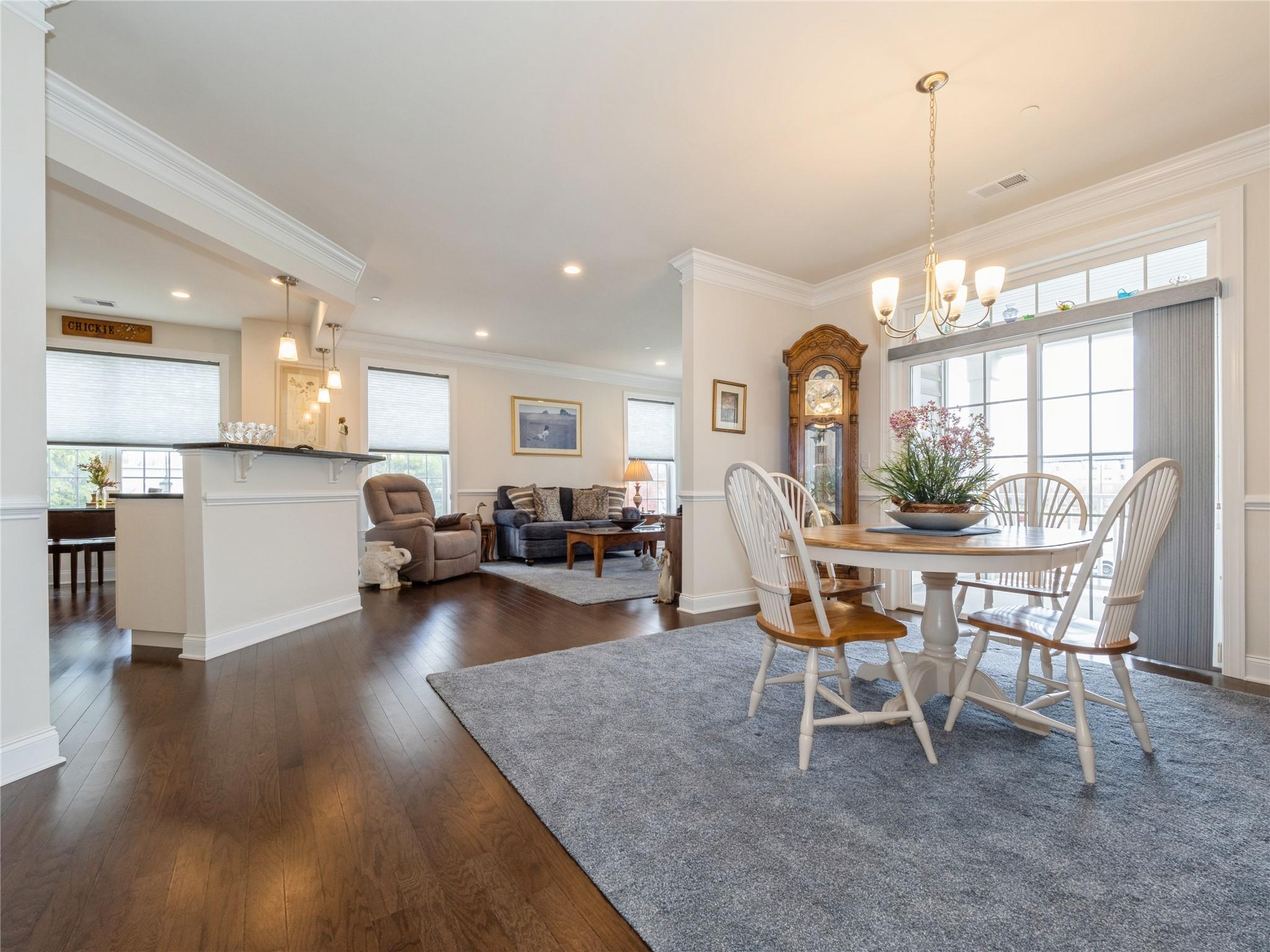 Dining area with ornamental molding, visible vents, an inviting chandelier, and dark wood-style flooring
