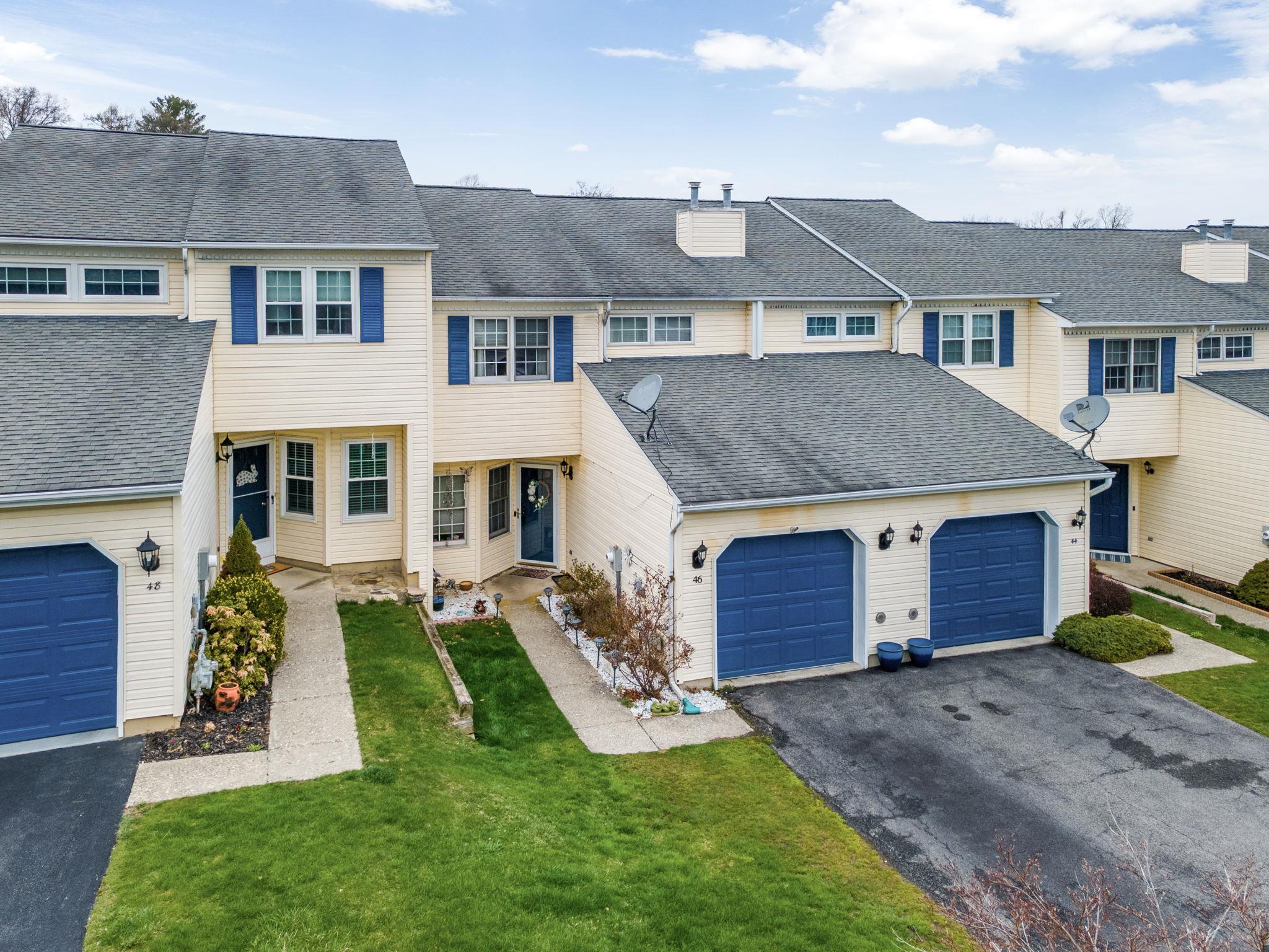 View of property with a front lawn, a chimney, a garage, a shingled roof, and aphalt driveway