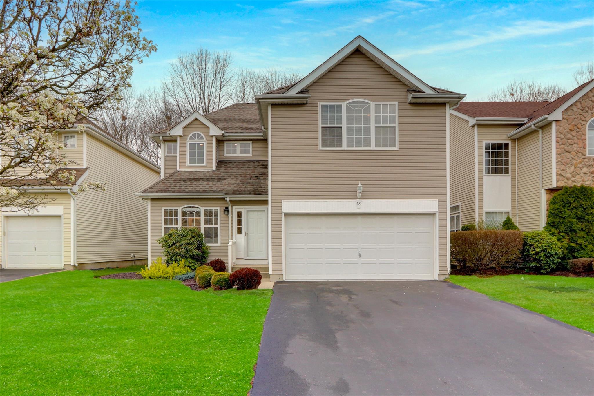 Traditional-style house featuring aphalt driveway, a shingled roof, an attached garage, and a front yard