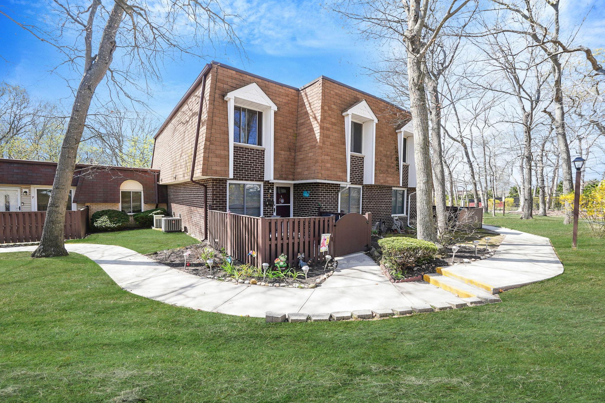 View of home's exterior with central AC unit, a yard, mansard roof, brick siding, and a deck