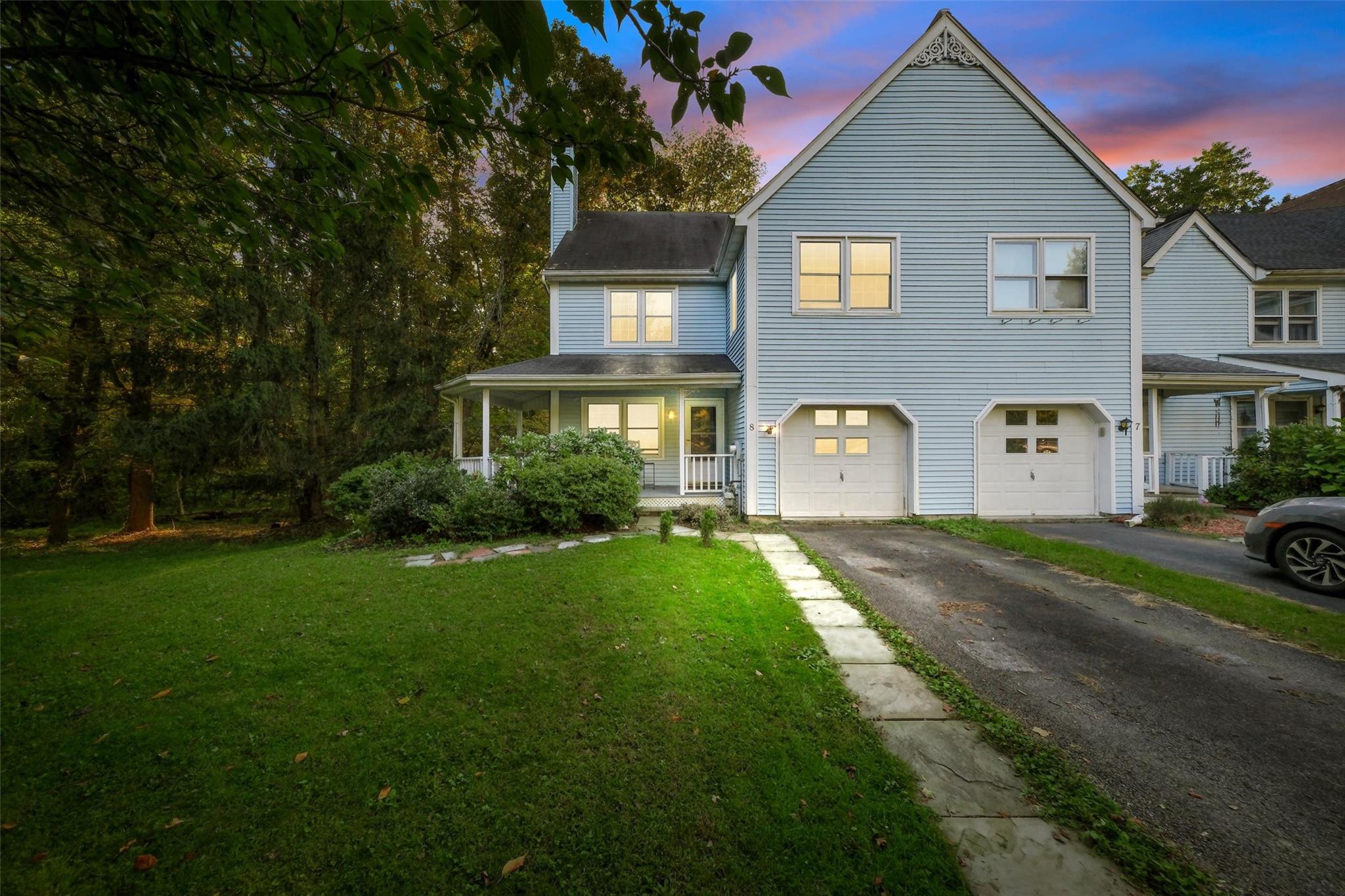 Traditional-style home with a lawn, driveway, covered porch, and a garage