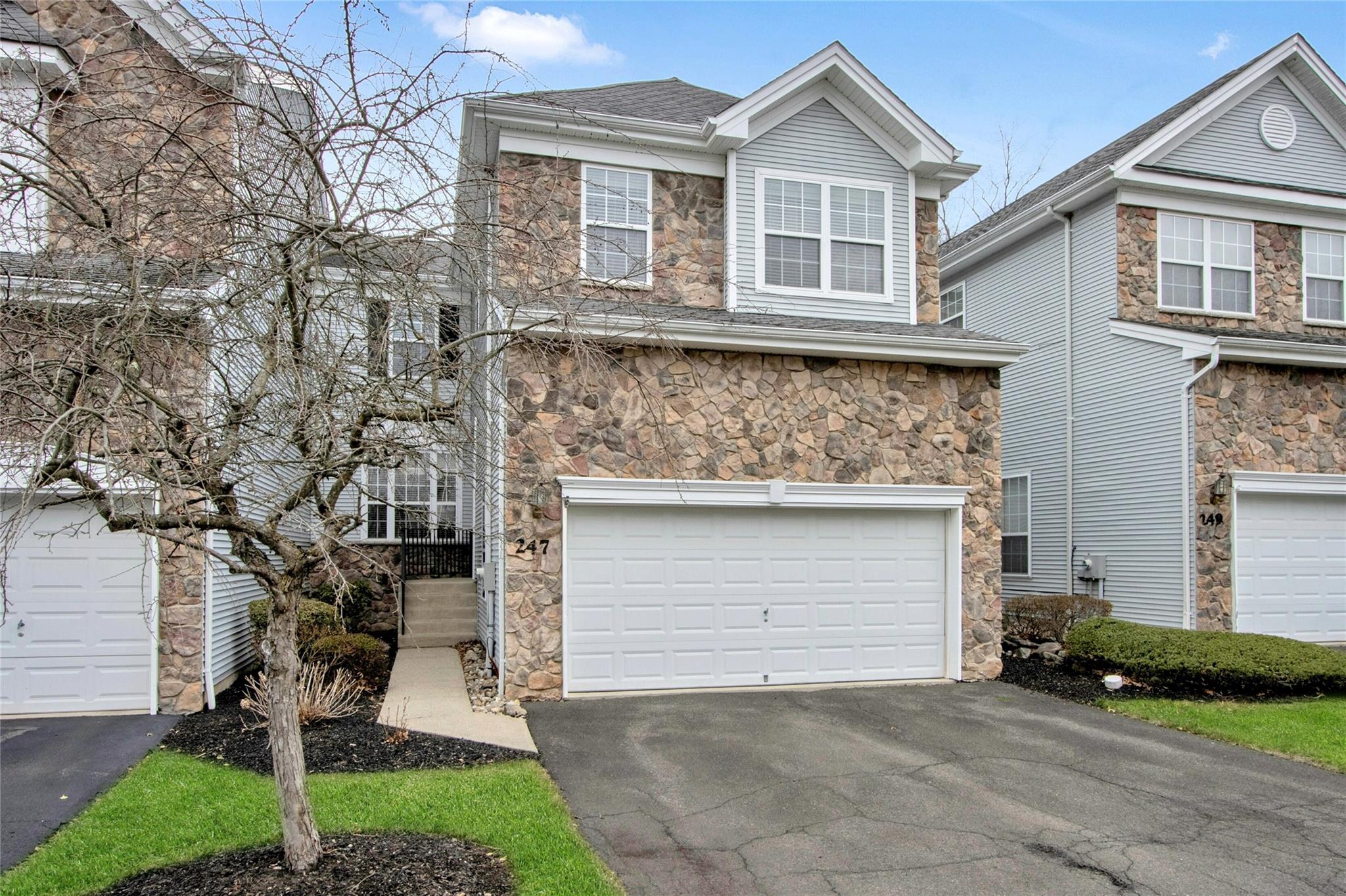 Traditional-style home featuring a garage, driveway, and stone siding