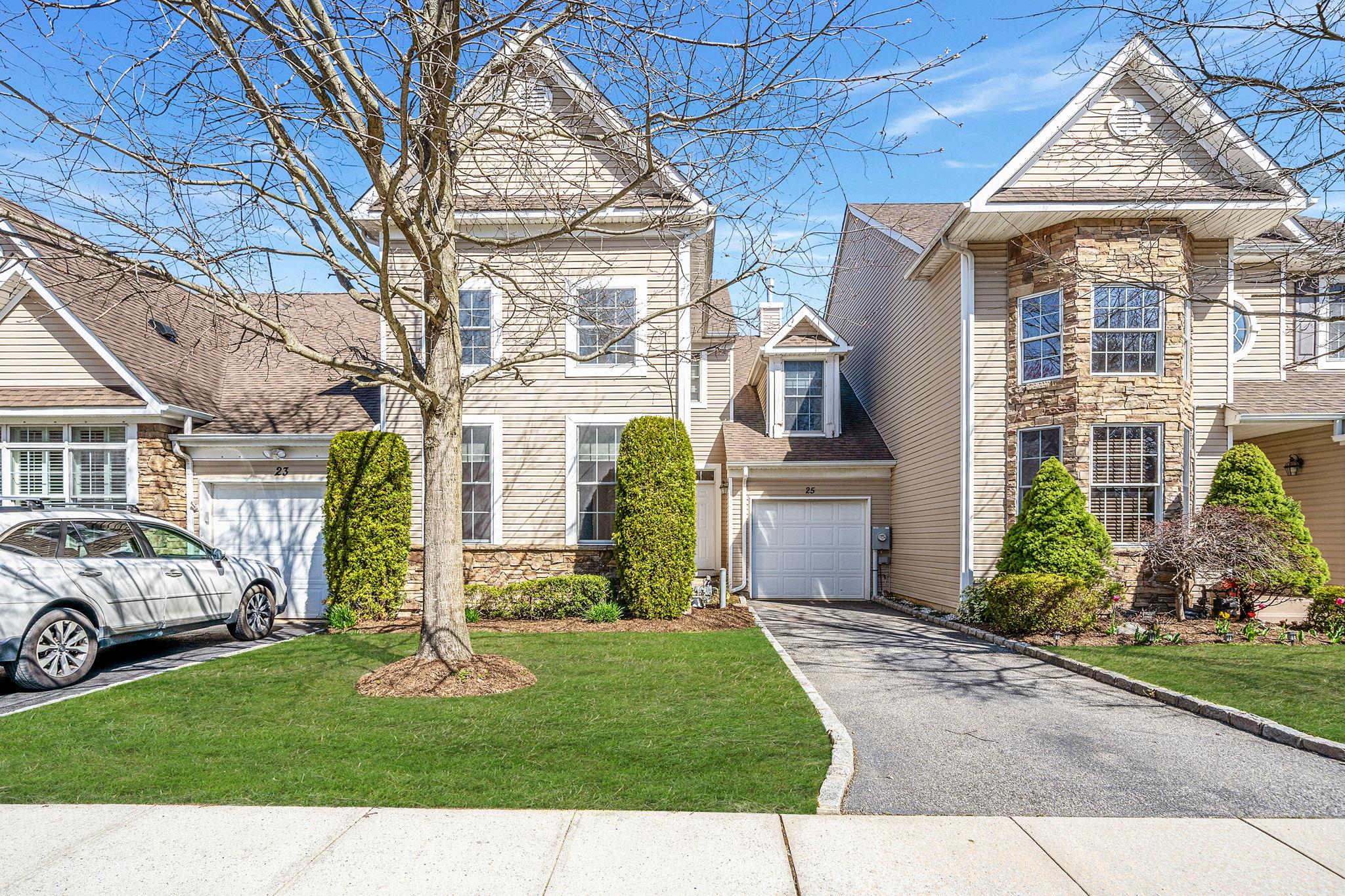 Traditional home with driveway, stone siding, a shingled roof, a front yard, and a garage