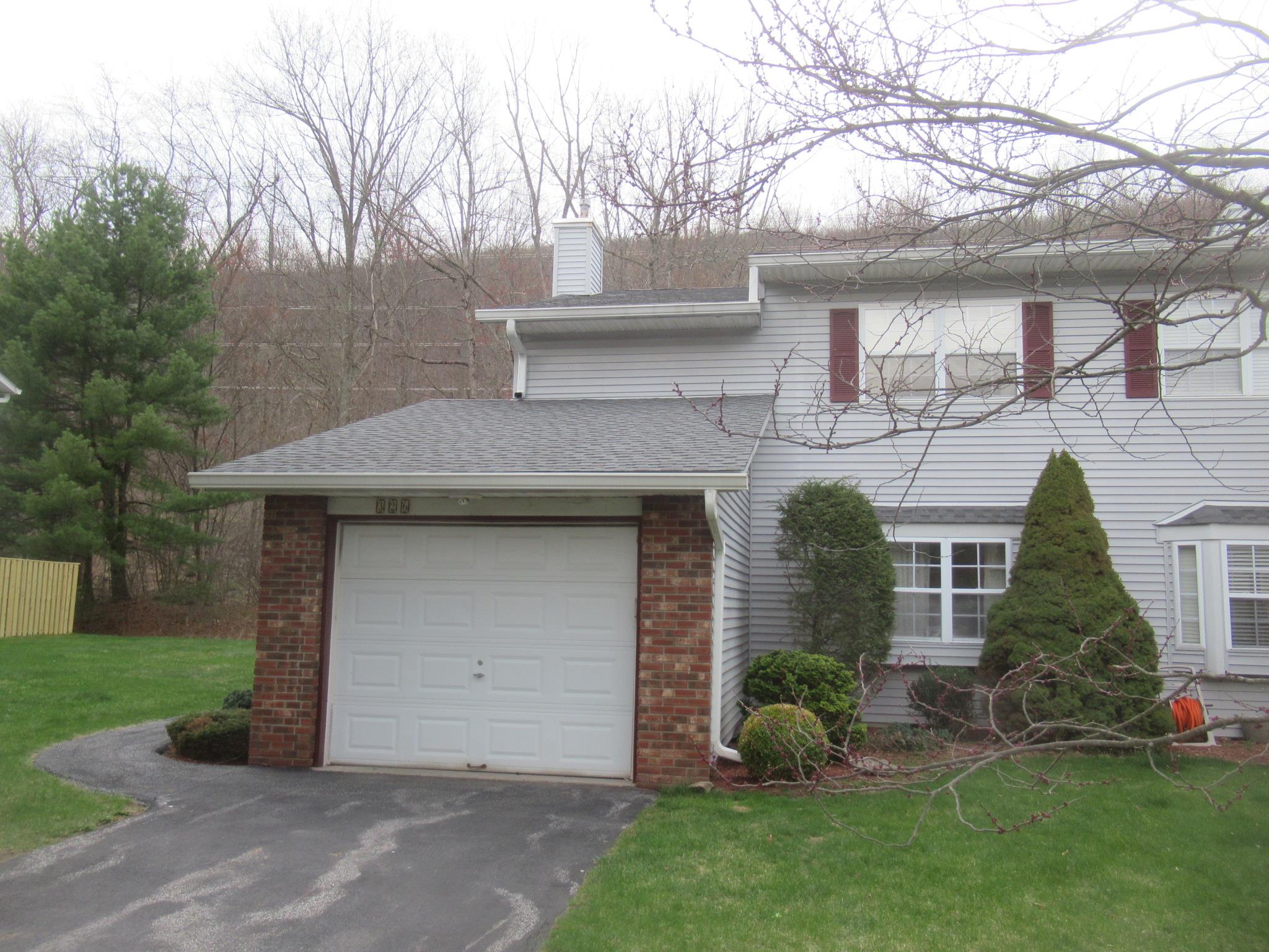 View of front facade with a chimney, driveway, a front yard, and brick siding