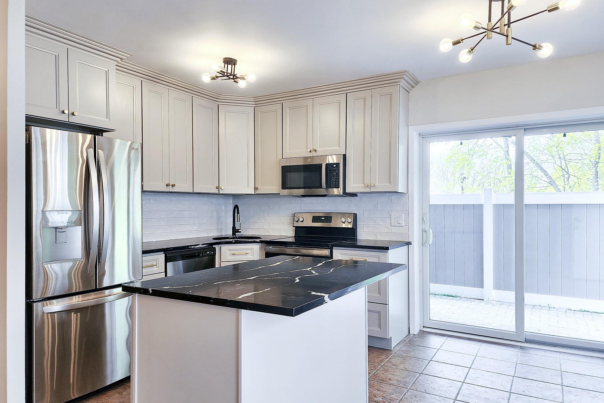 Kitchen featuring an inviting chandelier, dark countertops, a sink, decorative backsplash, and appliances with stainless steel finishes