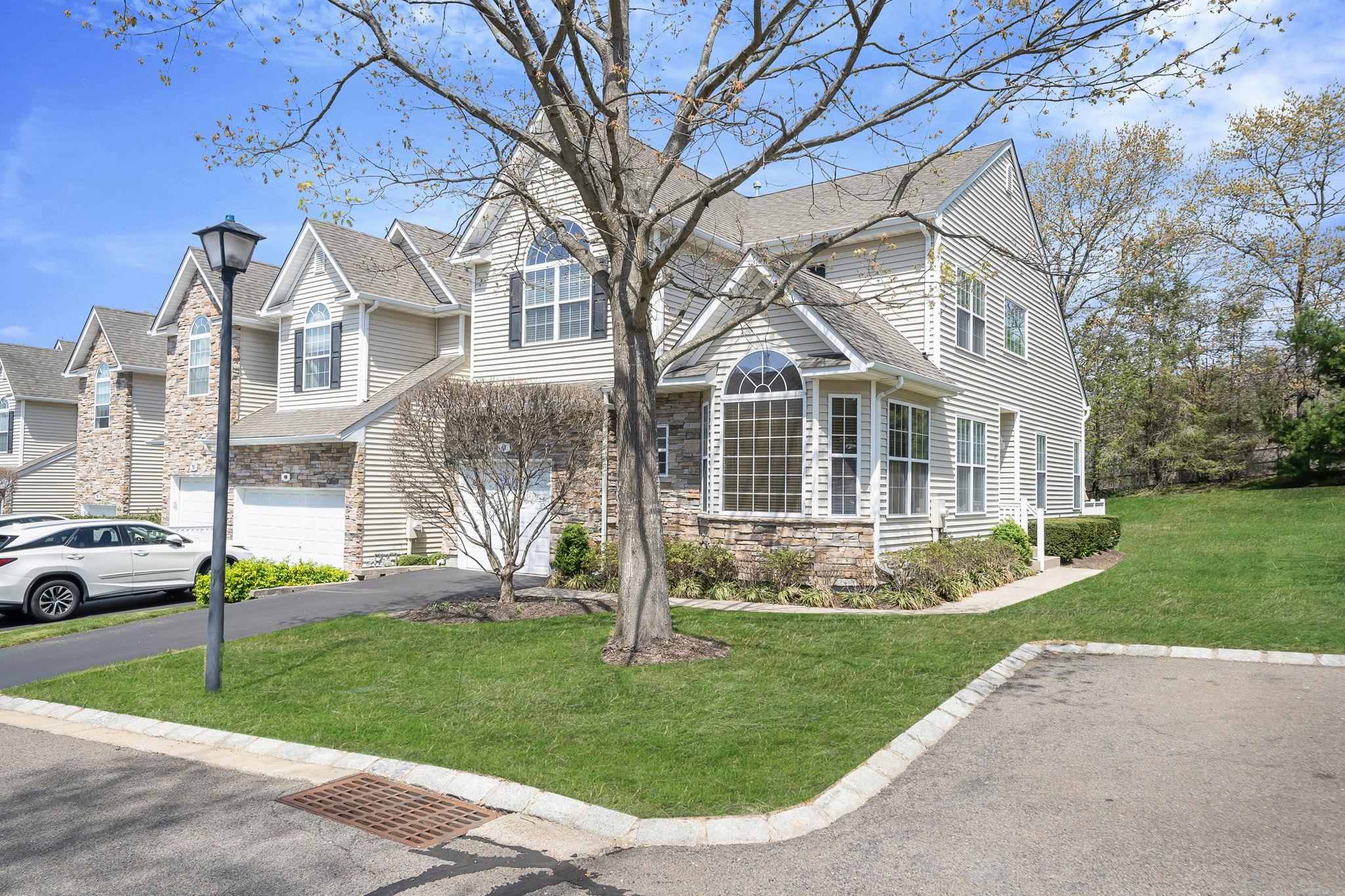 View of front of property with an attached garage, aphalt driveway, stone siding, and a front yard