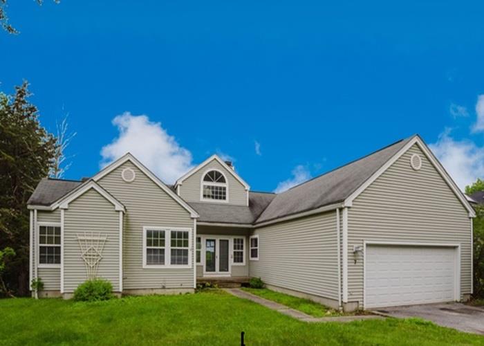 View of front facade featuring driveway, a front yard, and a garage