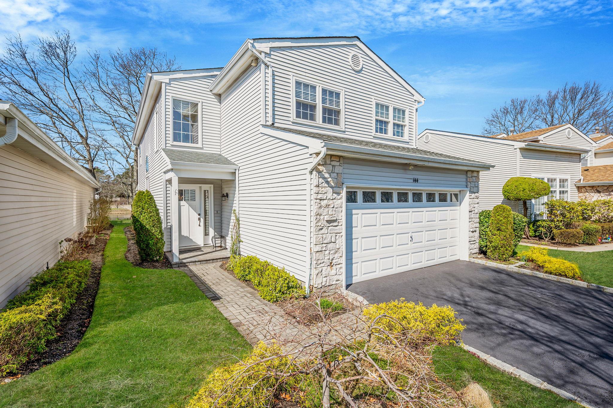 View of front of home with an attached garage, driveway, stone siding, and a front lawn