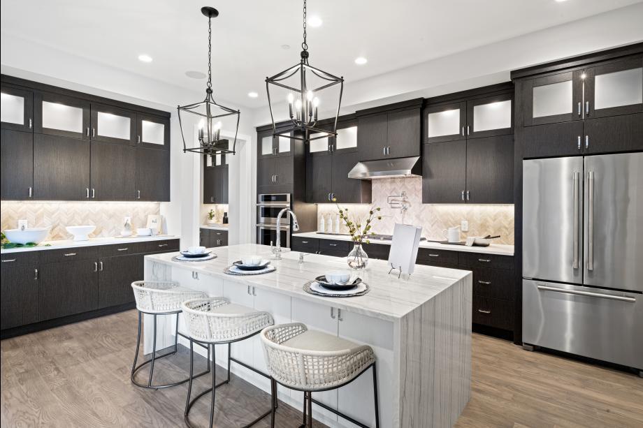 Kitchen featuring decorative backsplash, light wood-style flooring, stainless steel appliances, under cabinet range hood, and a notable chandelier