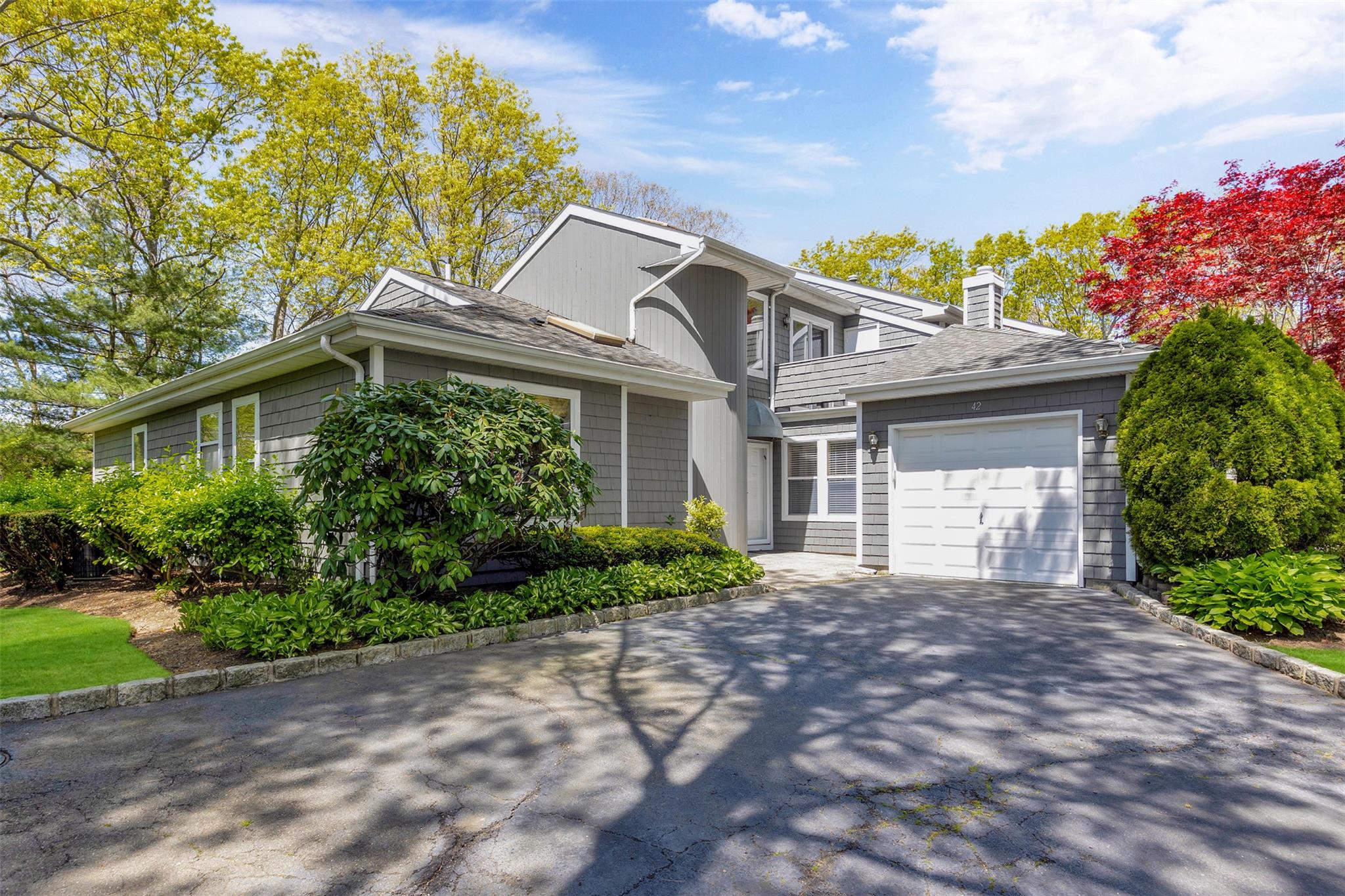 View of front of home with an attached garage, aphalt driveway, roof with shingles, and a chimney