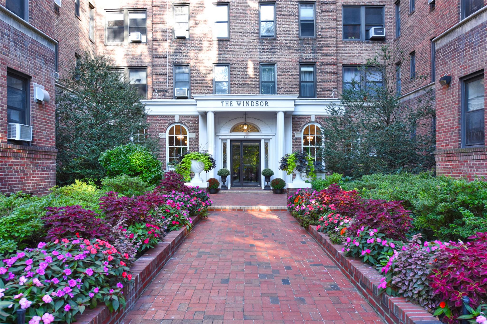 View of exterior entry with cooling unit and brick siding
