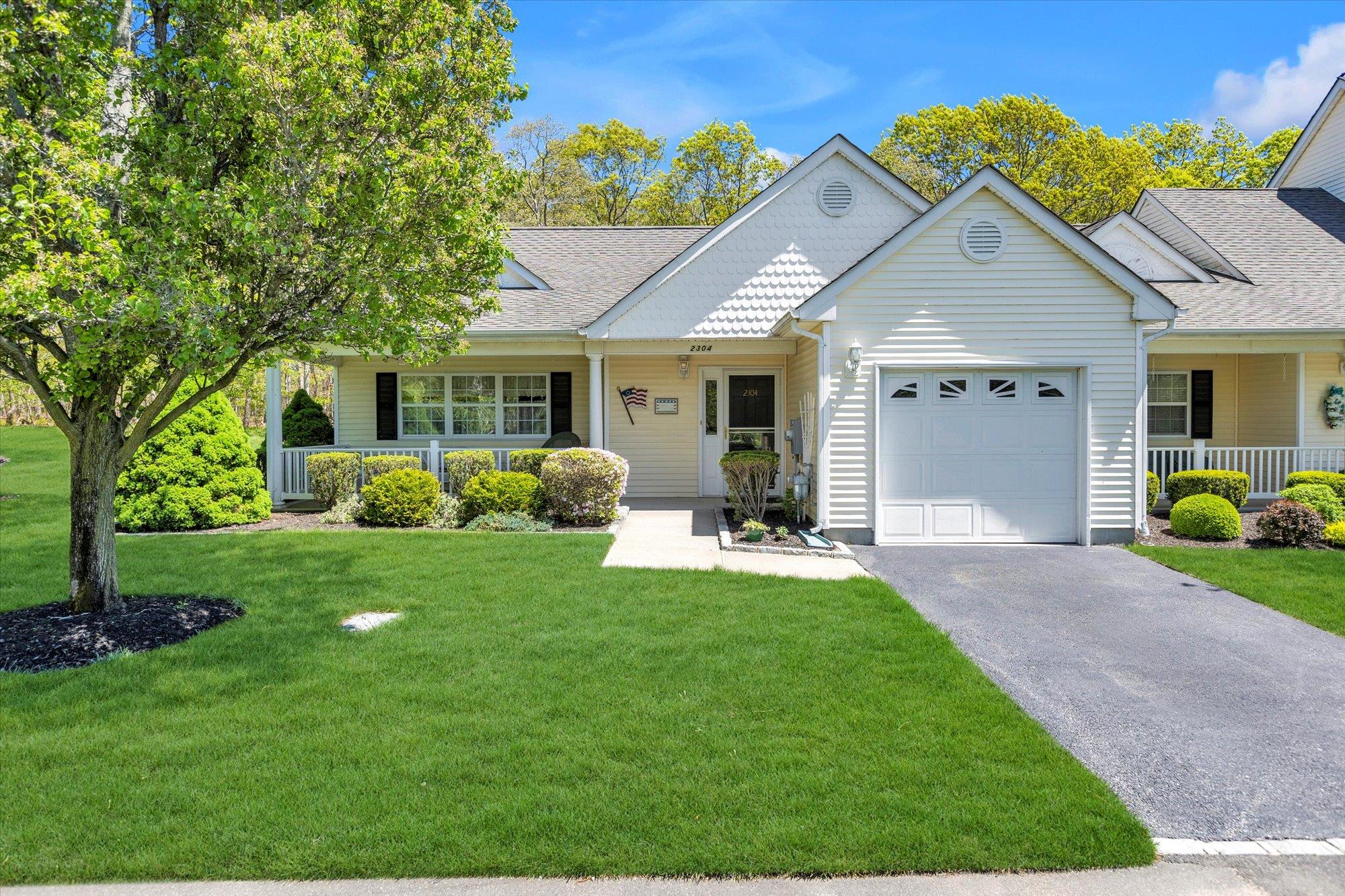 View of front of home with covered porch, a garage, asphalt driveway, and a front yard