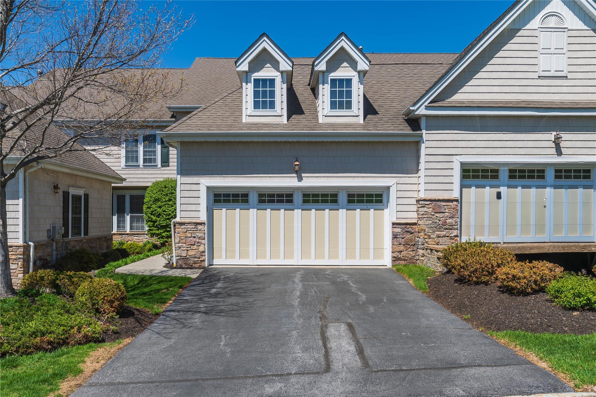 View of front of property with a garage, a shingled roof, driveway, and stone siding