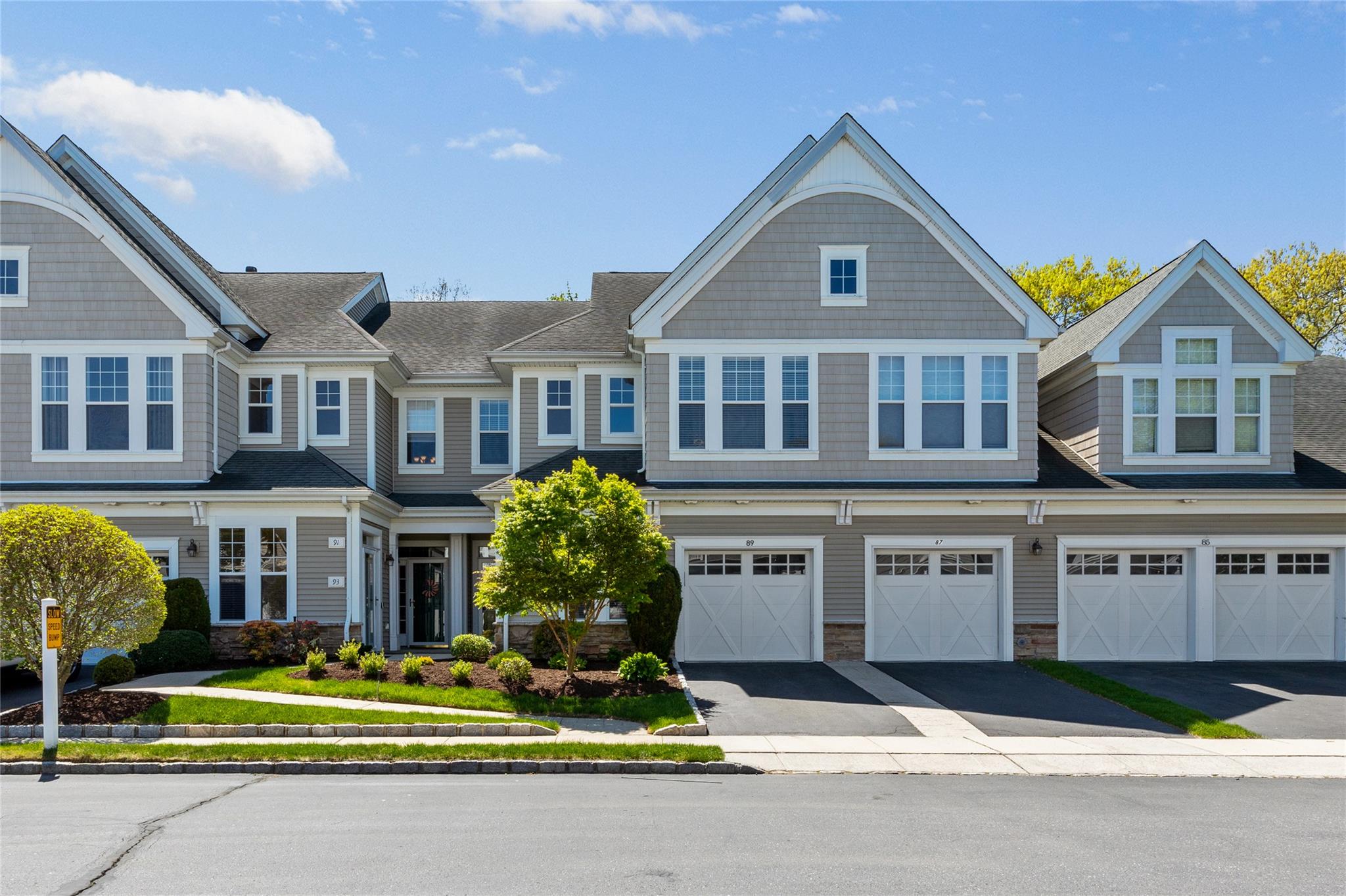 Multi unit property with an attached garage, driveway, and stone siding