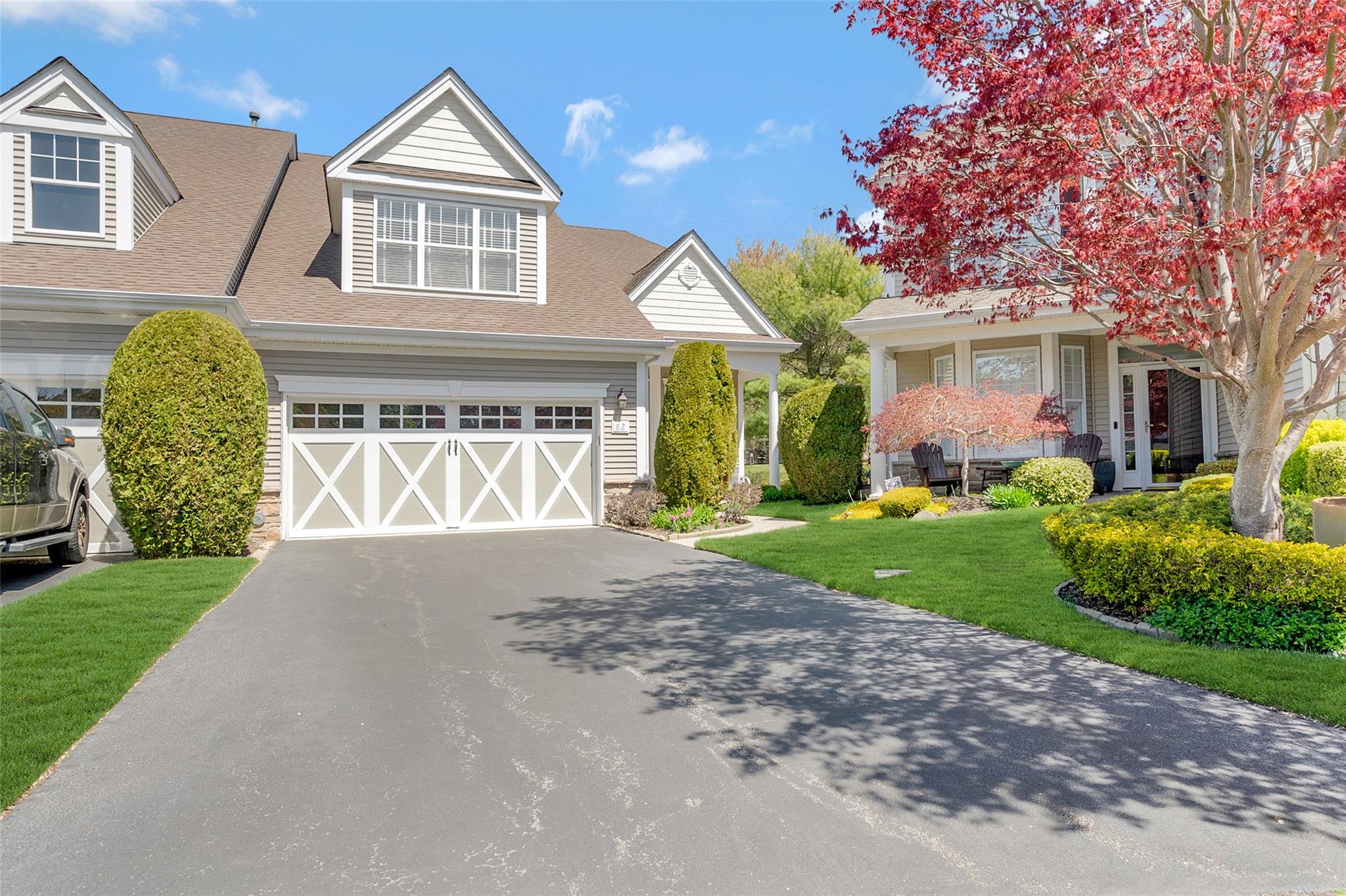 View of front facade featuring an attached garage, driveway, roof with shingles, and a front lawn
