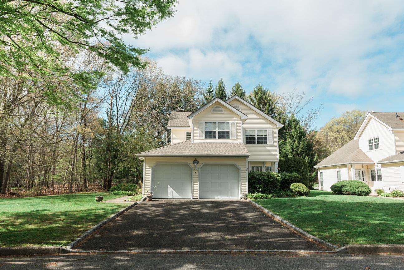 View of front facade featuring a garage, roof with shingles, driveway, and a front yard