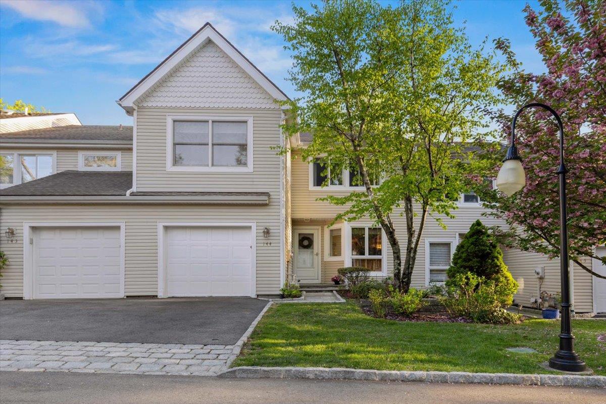 View of front facade with an attached garage, a front yard, and aphalt driveway