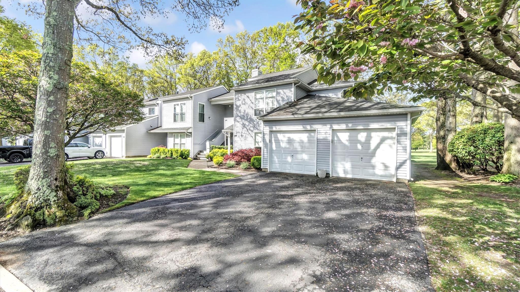 View of front of house with an attached garage, driveway, a front yard, and a chimney
