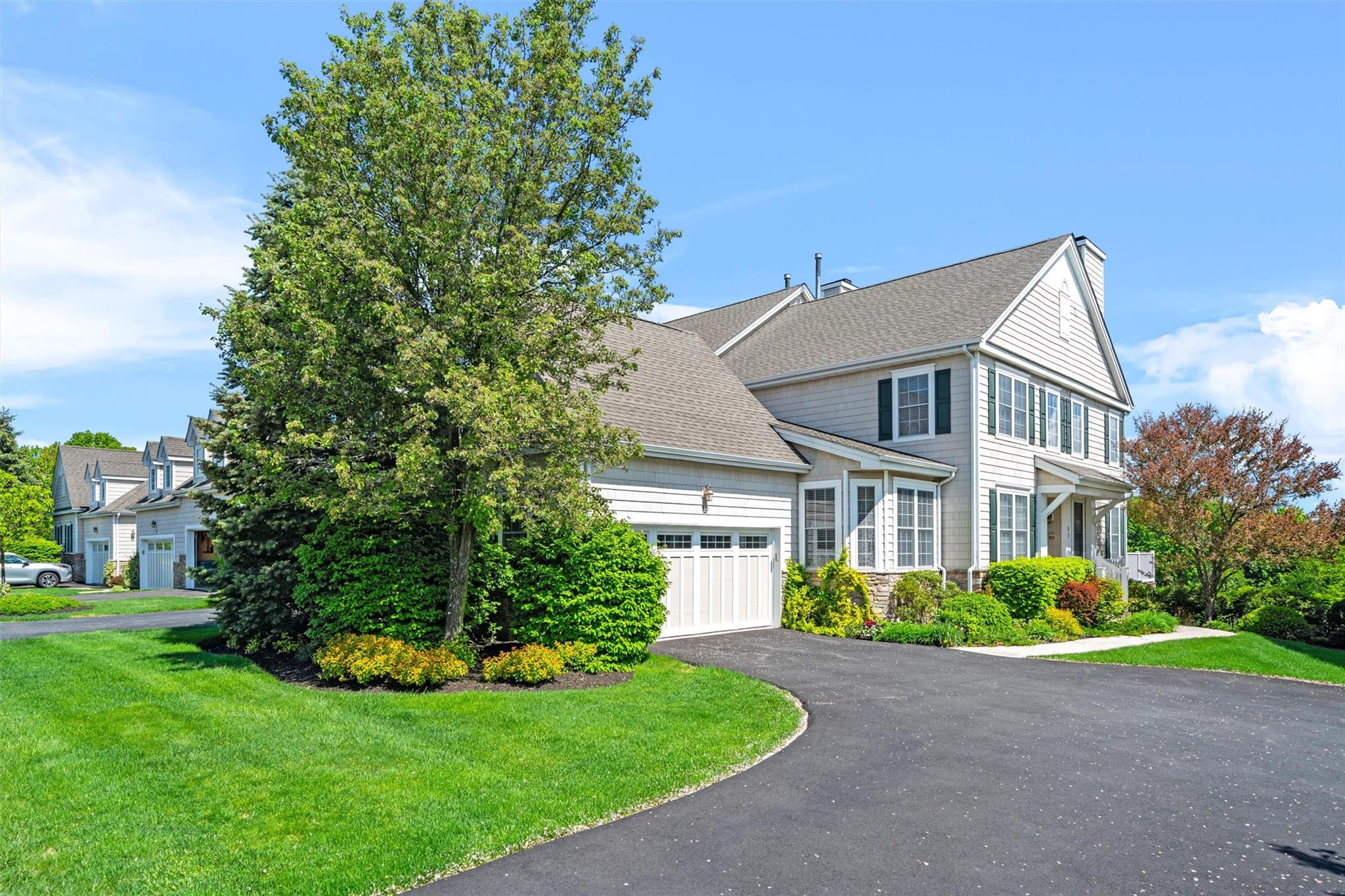 View of front of house with asphalt driveway, a garage, a front yard, and roof with shingles