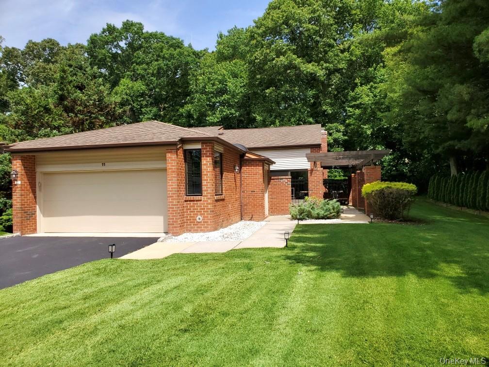 View of front facade with brick siding, driveway, a front yard, a garage, and a shingled roof