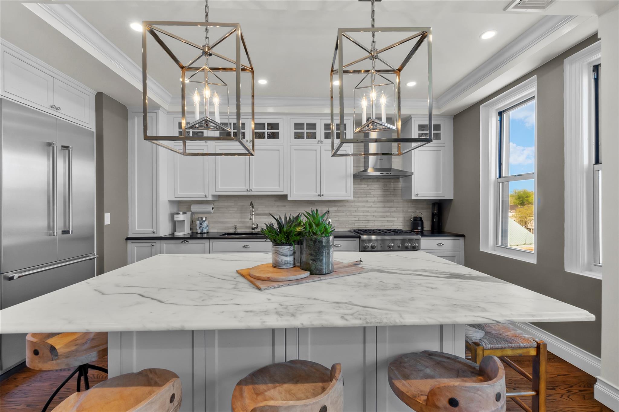 Kitchen with stainless steel appliances, a chandelier, ornamental molding, backsplash, and recessed lighting