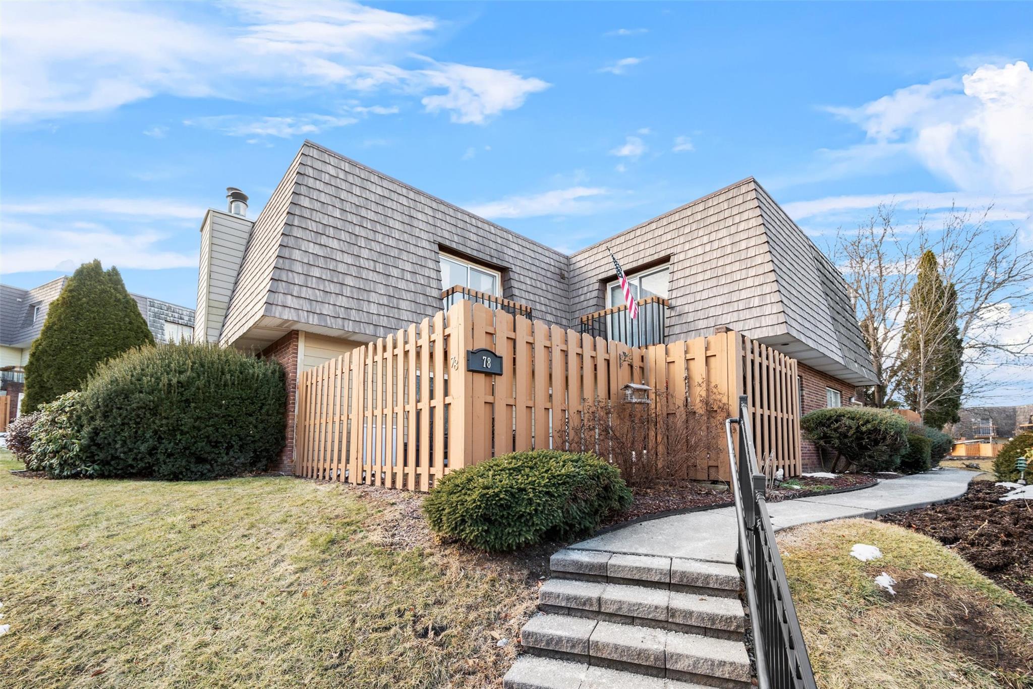 View of side of home with mansard roof, fence