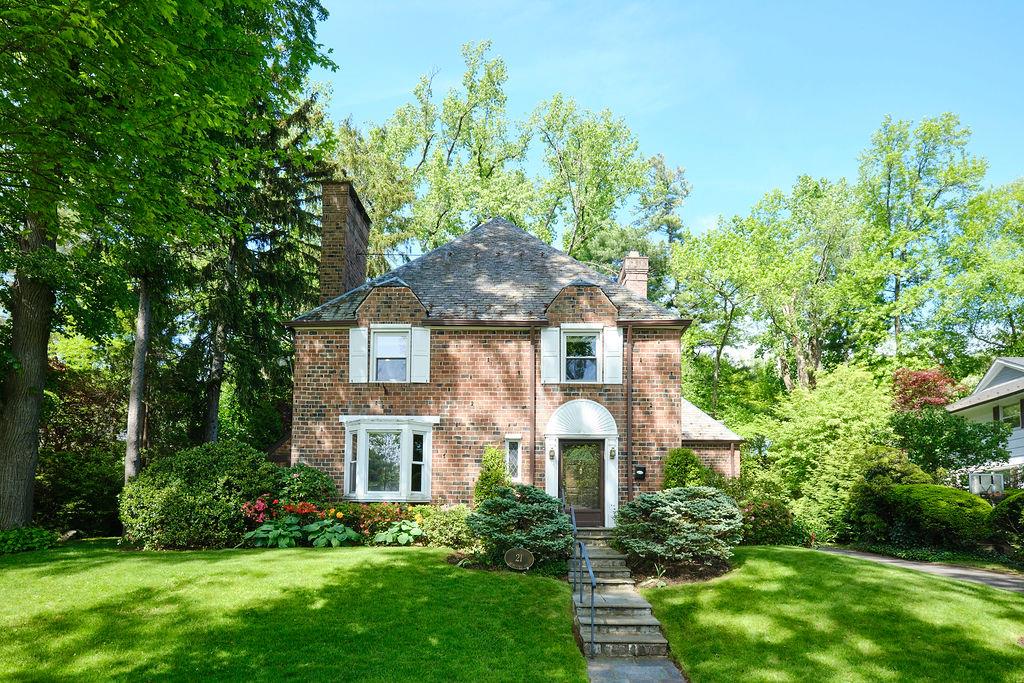 View of front of home with a chimney, a high end roof, a front lawn, and brick siding