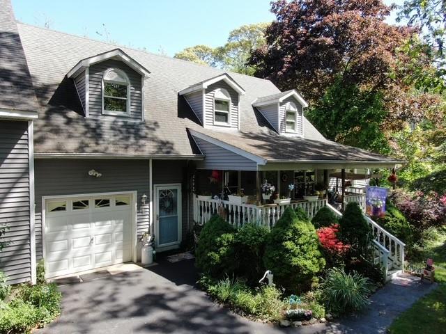 View of front of property with covered porch, a garage, and asphalt driveway