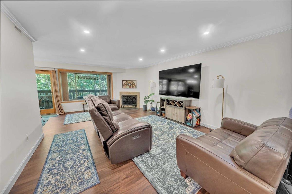 Living room with vinyl finished floors, ornamental molding, recessed lighting, baseboards, and a fireplace