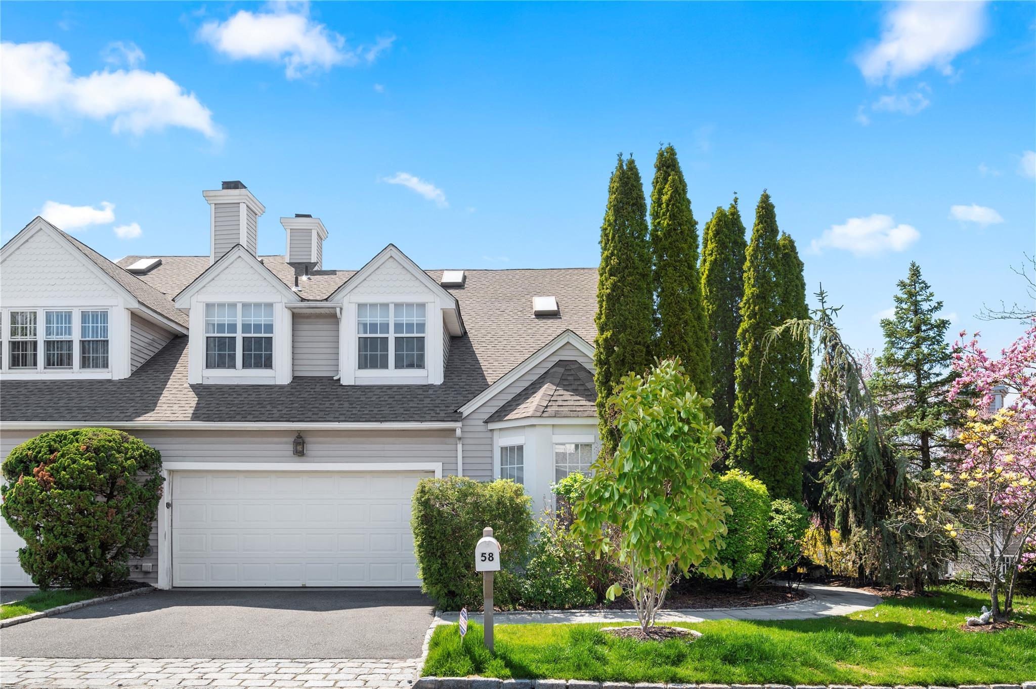 View of front of house featuring roof with shingles, driveway, an attached garage, and a chimney