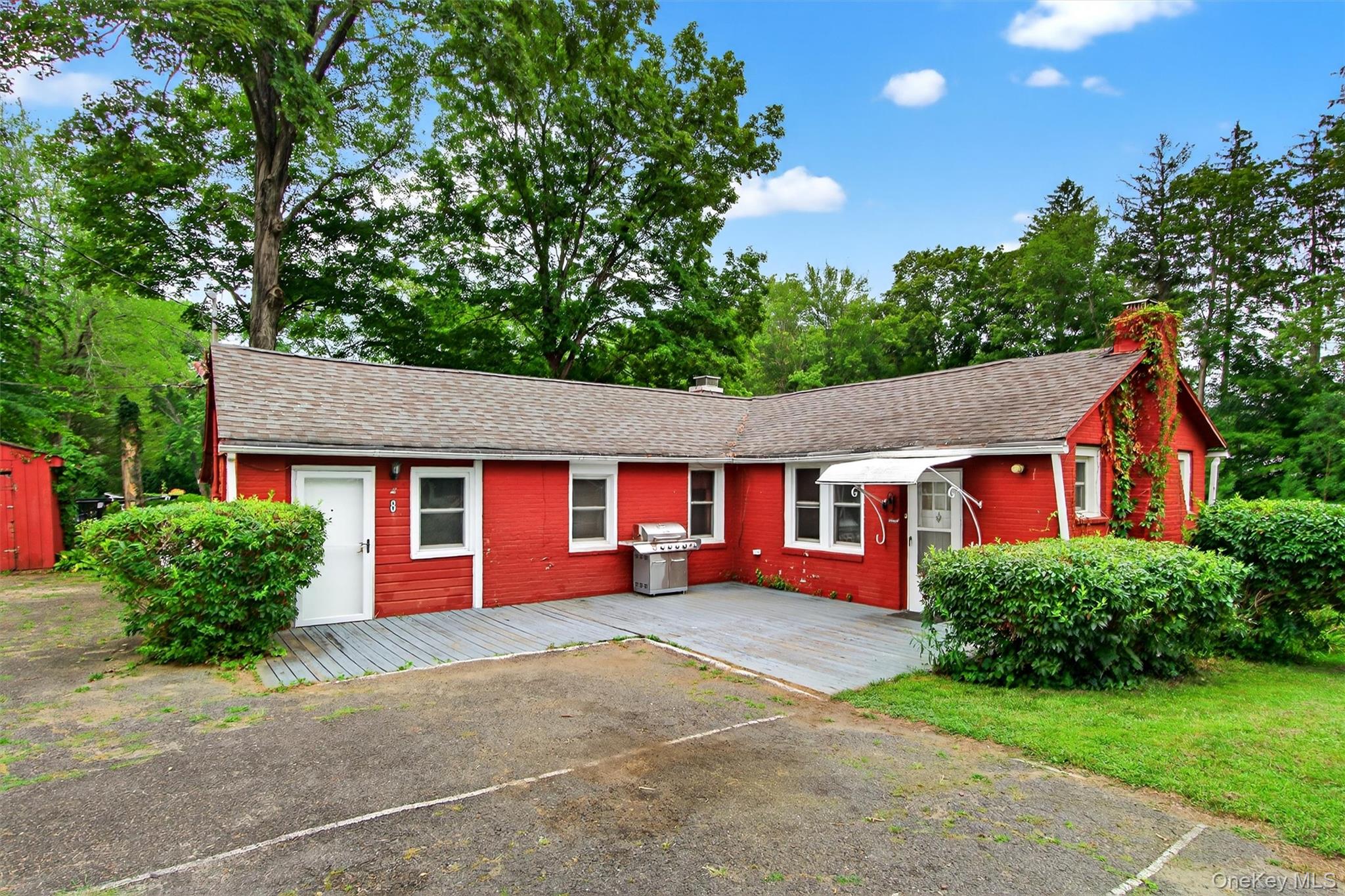 View of front of property with a chimney, roof with shingles, and a wooden deck