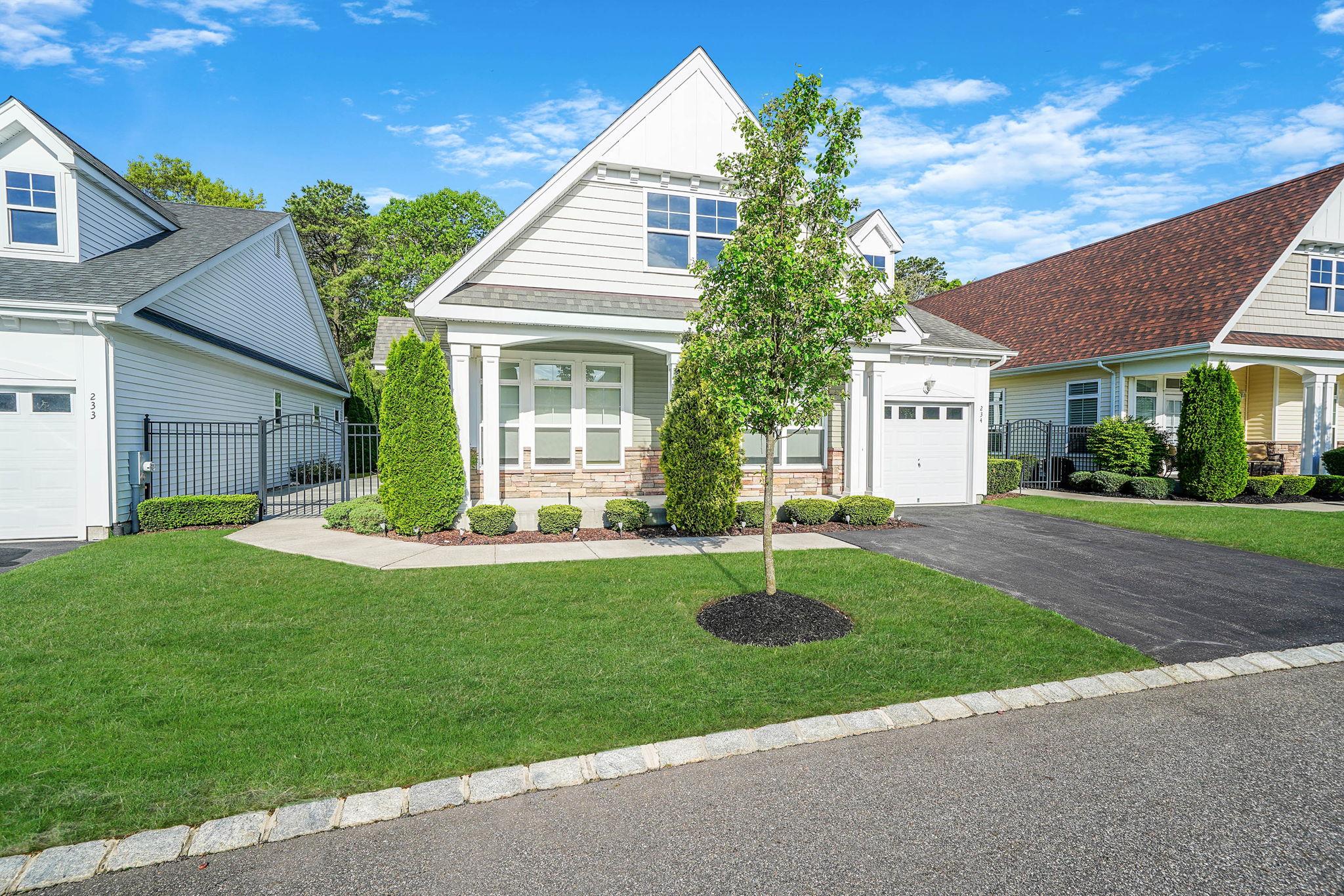 View of front of property with asphalt driveway, covered porch, stone siding, and a shingled roof
